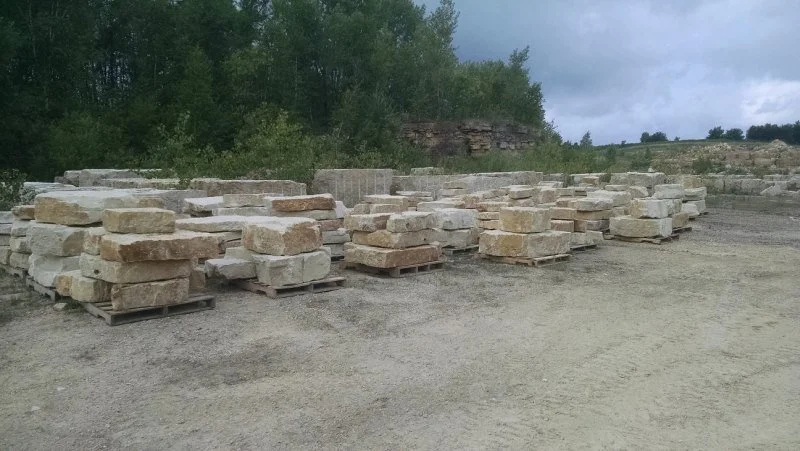 Stacks of stone bricks on pallets in an outdoor storage area.