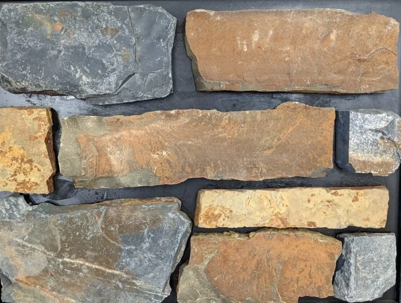 Stacked pieces of natural stone with varying textures and colors, arranged in an uneven pattern.
