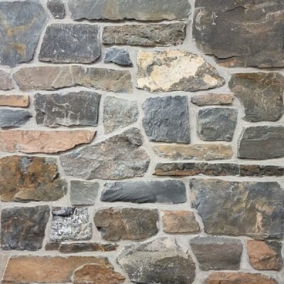 Close-up of a stone wall with variously colored and textured stones.