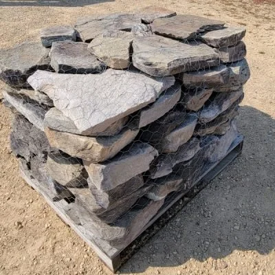 Stack of irregularly shaped flat stones on a wooden pallet outdoors.