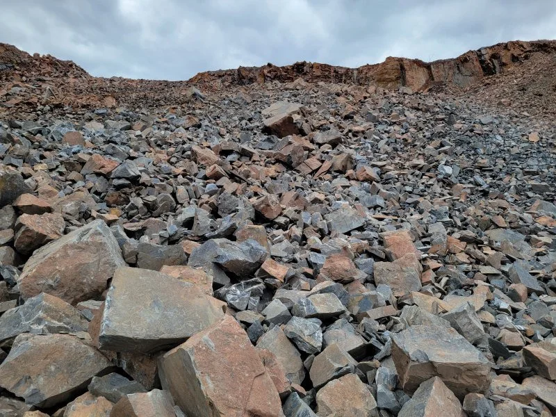 A rocky hillside with large and small stones under an overcast sky.
