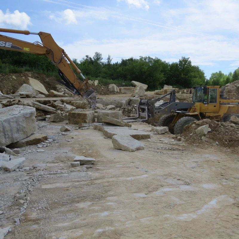 Construction site with excavator and loader moving large rocks and dirt.