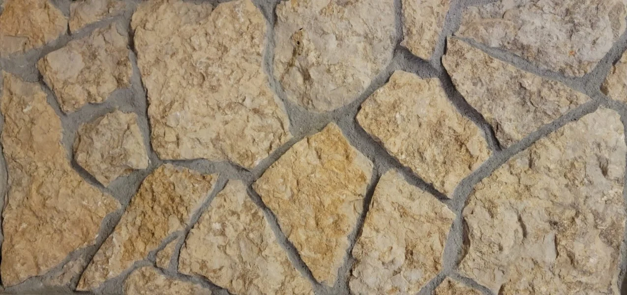 Close-up of irregularly shaped beige stone tiles arranged in a mosaic pattern with gray grout.