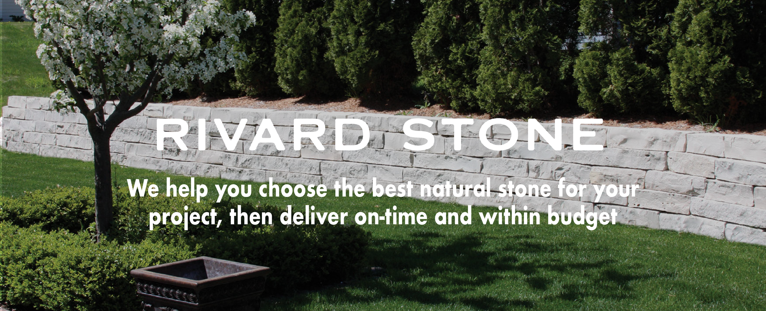 A landscaped garden with a stone retaining wall, a flowering tree, green shrubs, and grass, with text overlay promoting natural stone products from Rivard Stone.