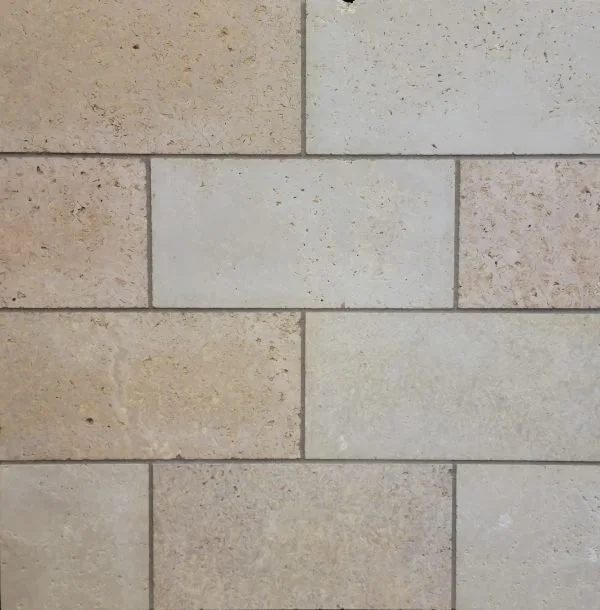Close-up of a beige stone brick wall with a horizontal rectangular brick in the middle.