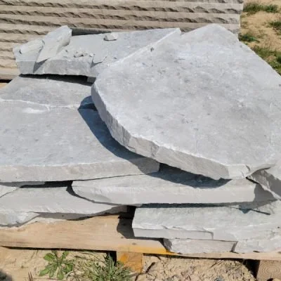 Stacked large flat grey stones on a wooden pallet outdoors.
