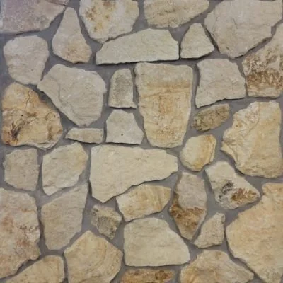 Close-up of a stone wall with irregular beige and tan stones.