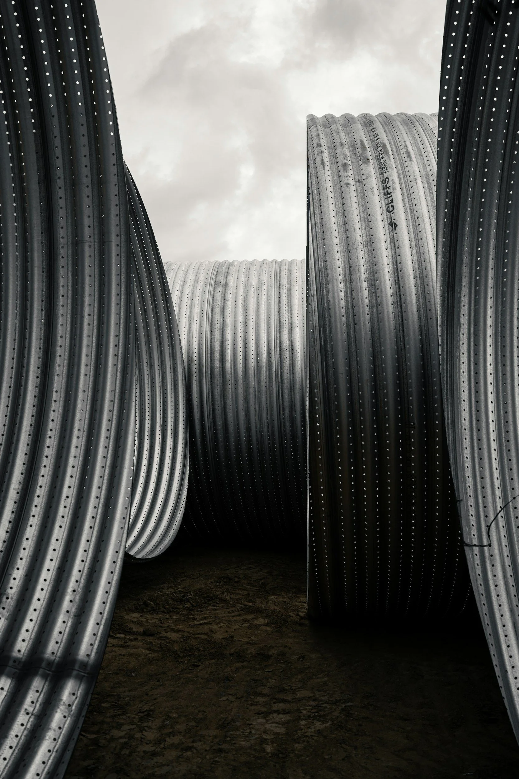 Close-up of large coiled metal cables with a cloudy sky in the background.