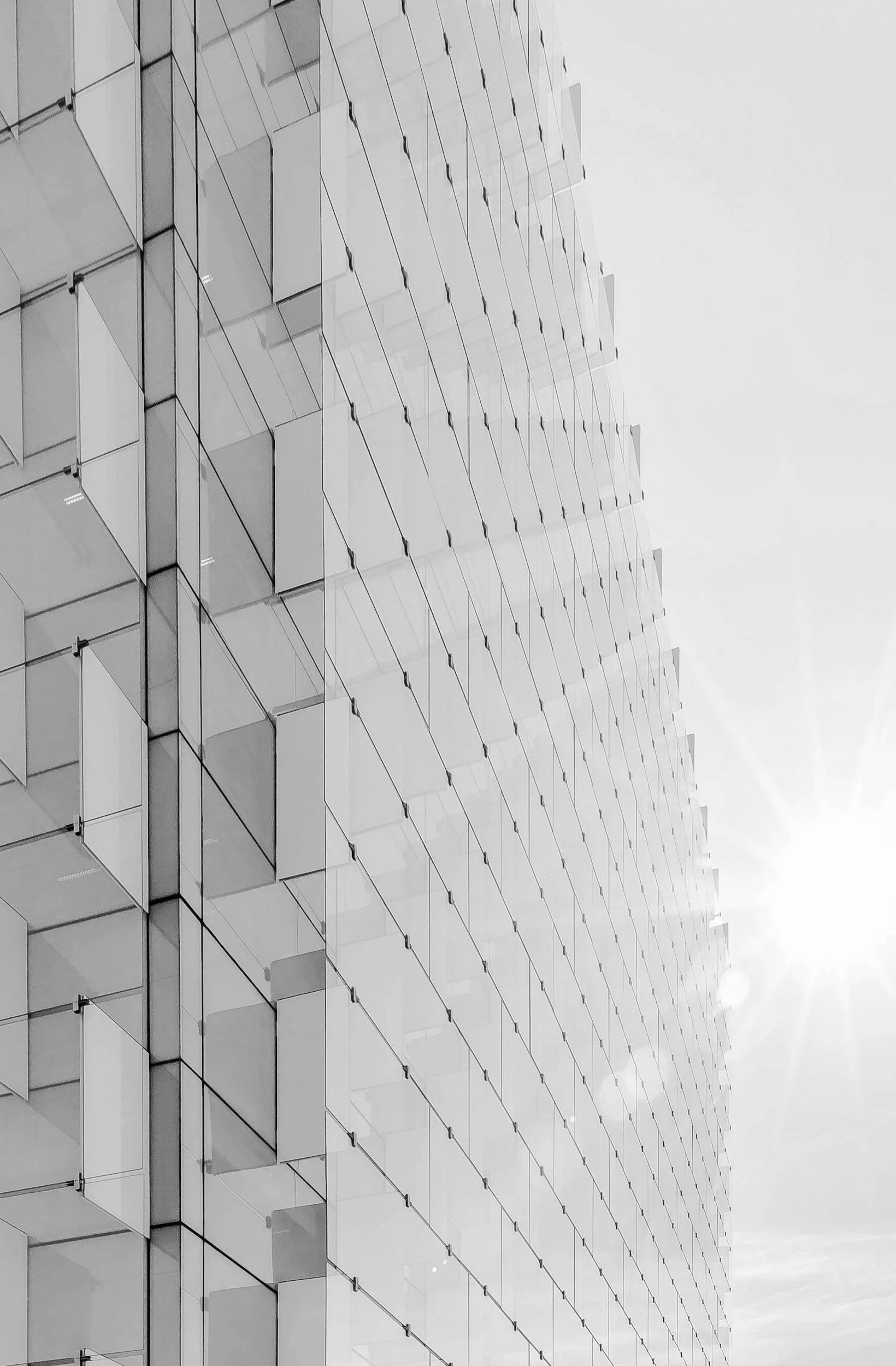 Close-up of a modern glass building with balconies, under bright sunlight.