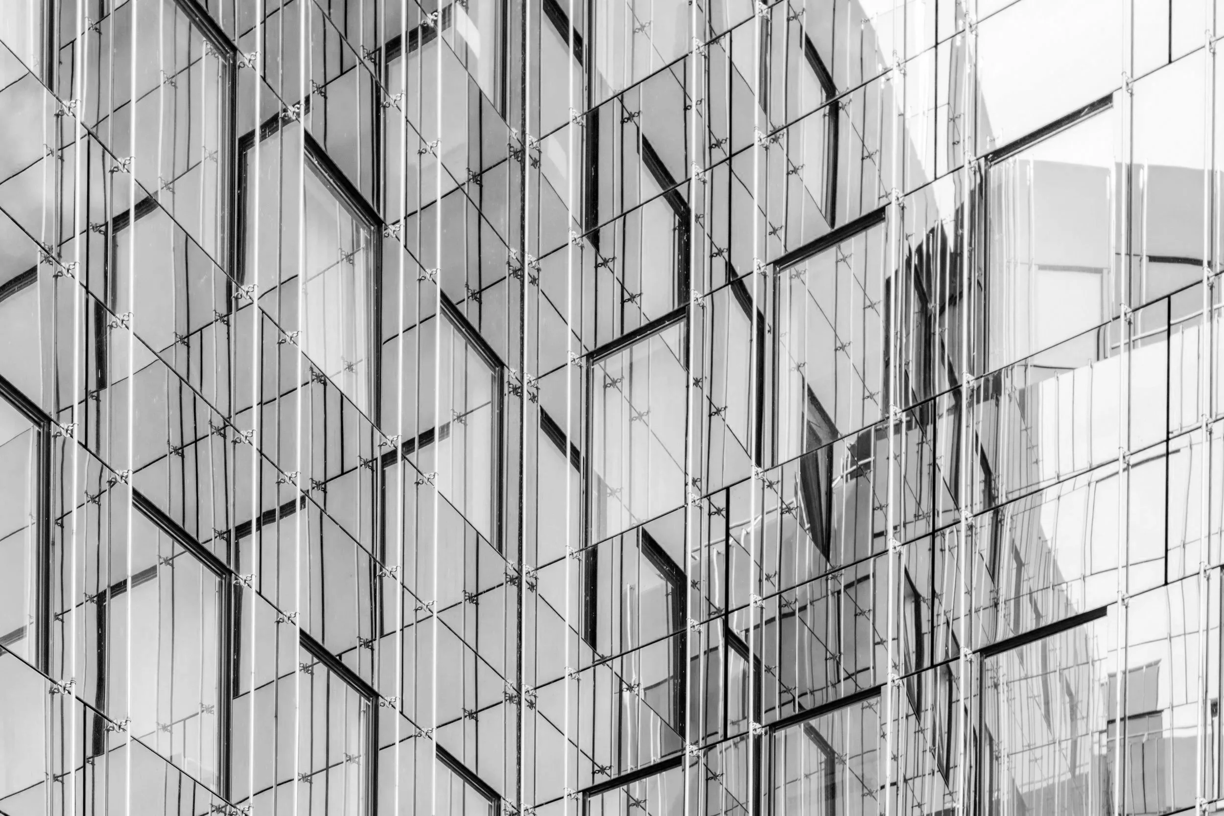 Close-up of a modern glass building with reflective windows and diagonal metal framework.