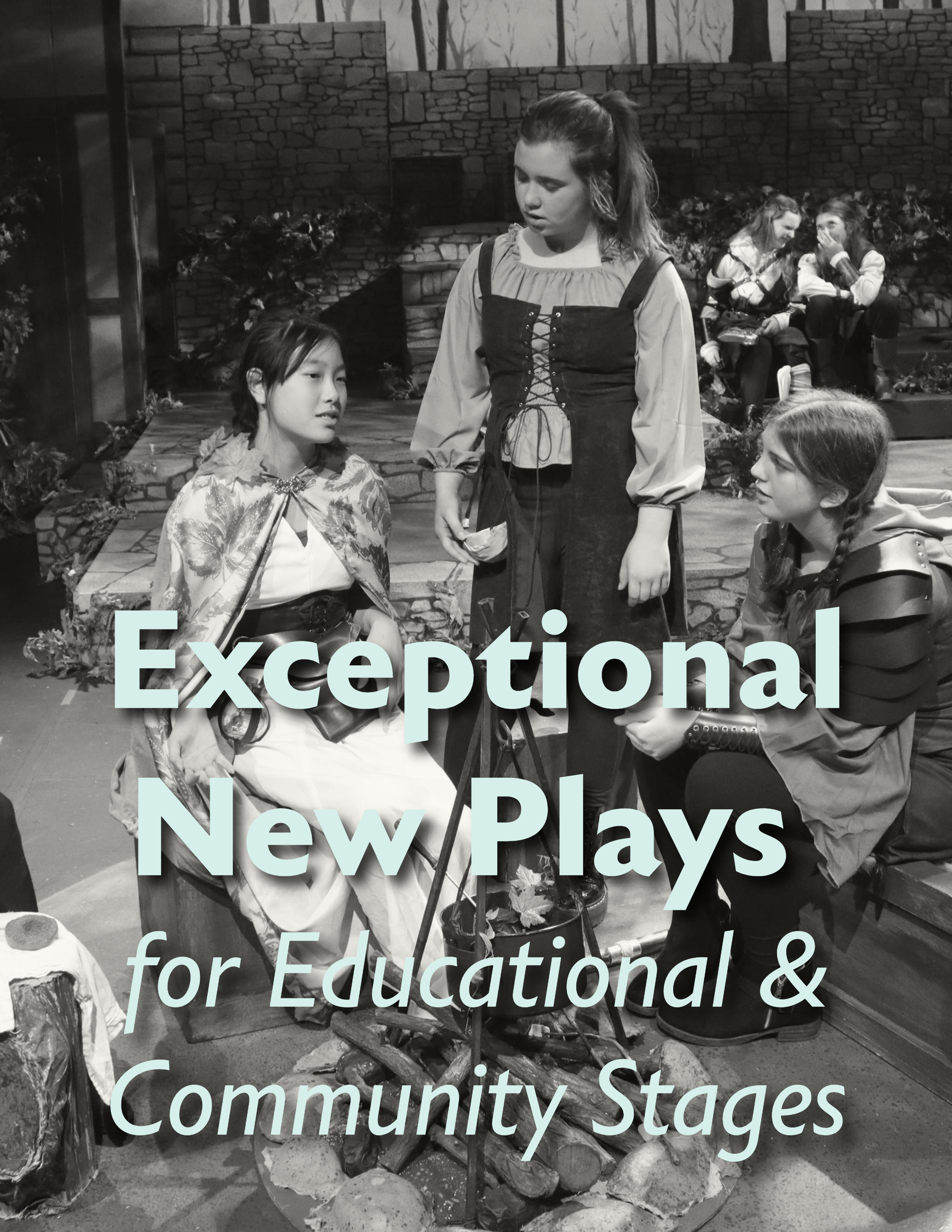 Three young girls in costumes participating in a community play, with two seated in the background and a brick wall behind them.