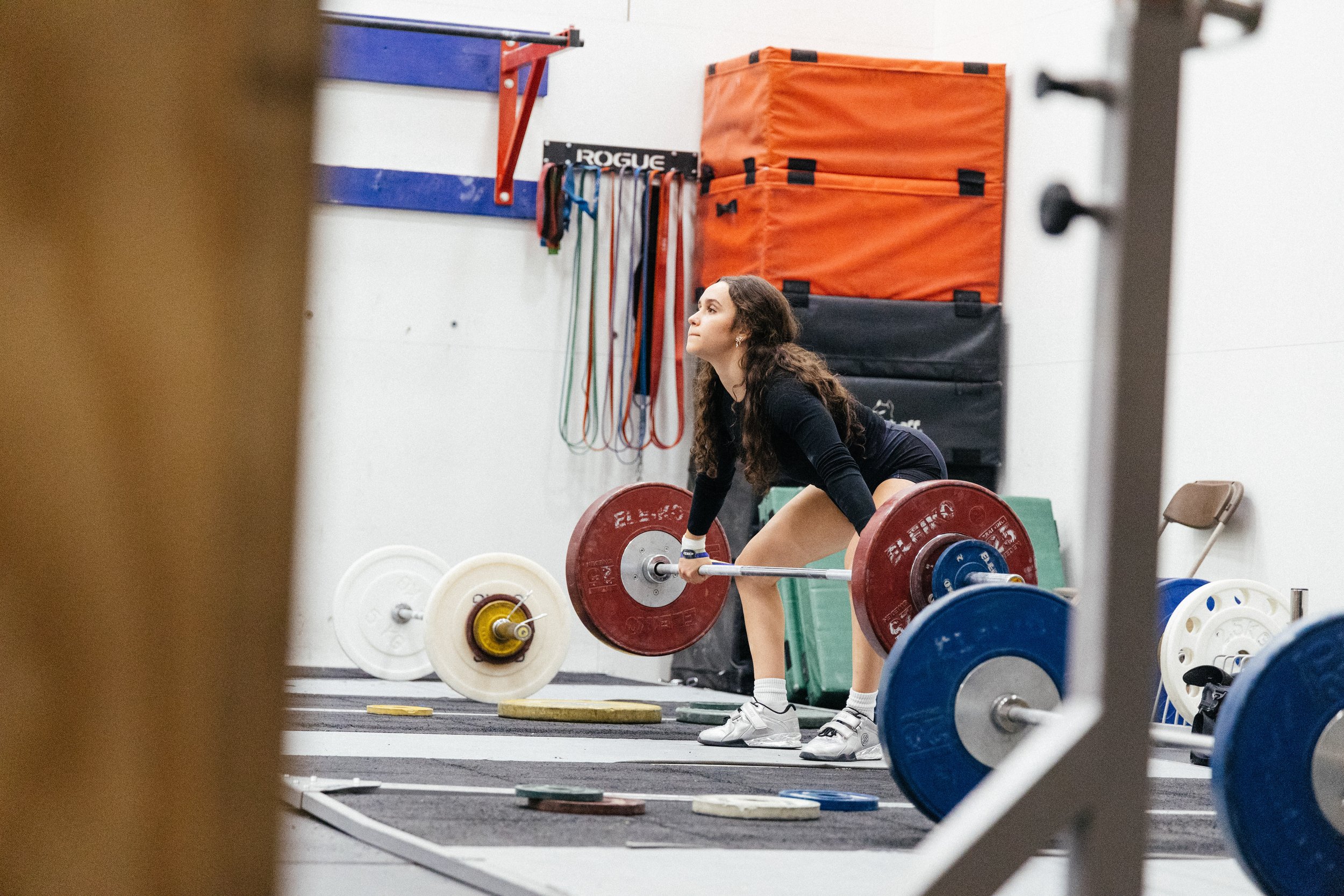 Une femme soulève une barre avec des poids lors d'une séance d'entraînement dans une salle de sport.