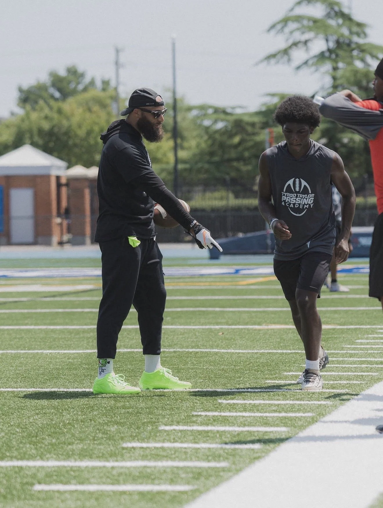 Coaching a quarterback on the field at the Tyrod Taylor Passing Academy in Hampton, Virginia.
