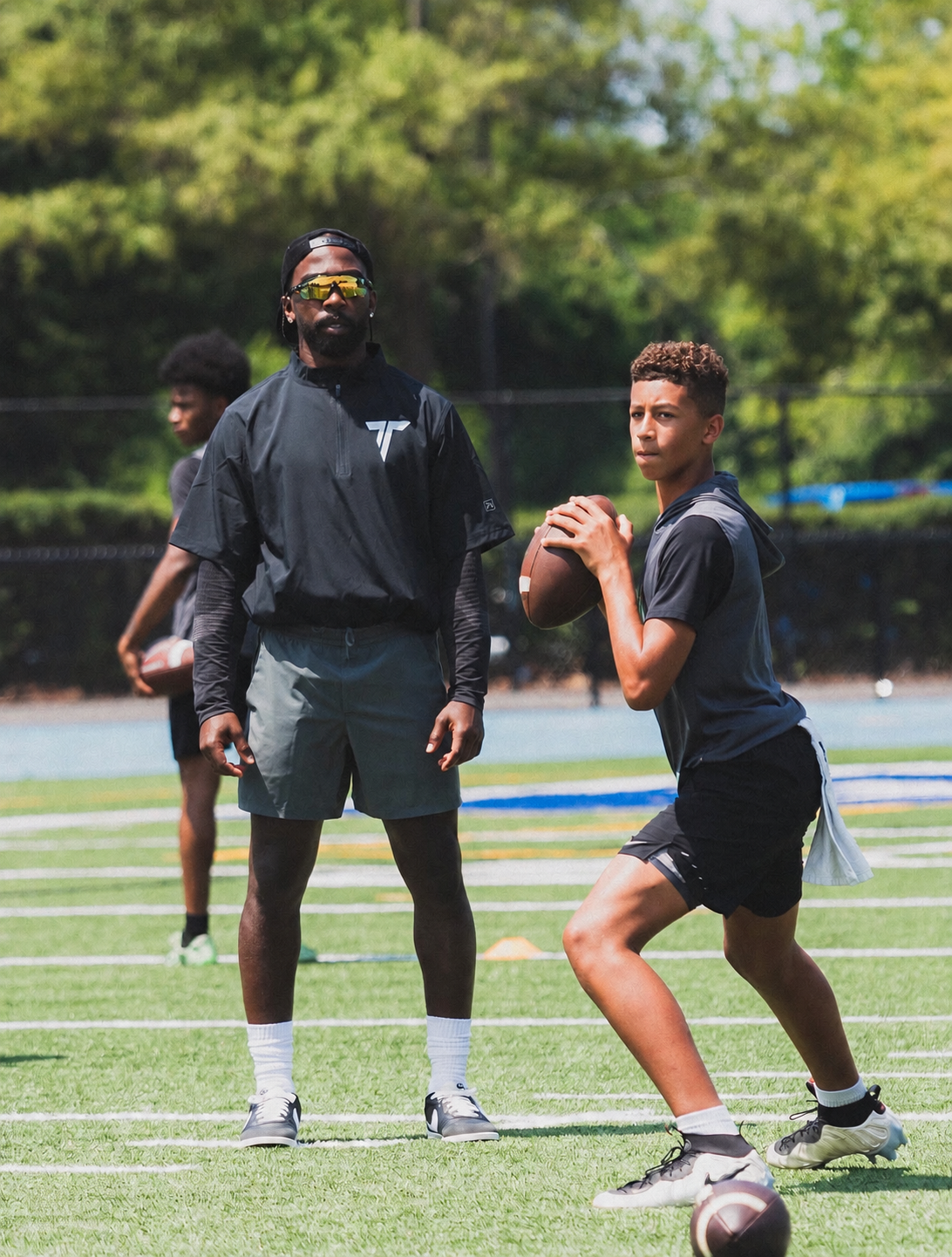 Tyrod Taylor working with a young quarterback at the passing academy.