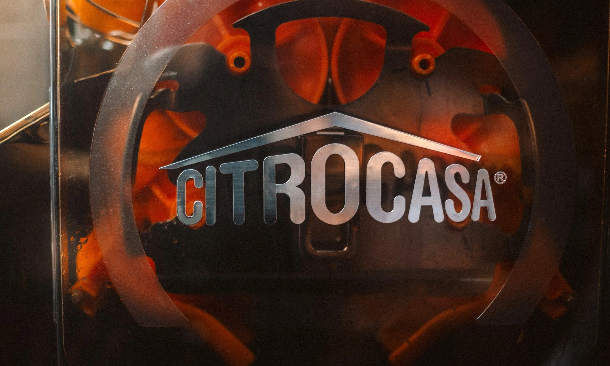 Das Bild zeigt ein Logo mit der Aufschrift 'CITROCASA' auf einer transparenten Oberfläche, mit einem Delphin in der Mitte, das von einem Kreis umgeben ist.