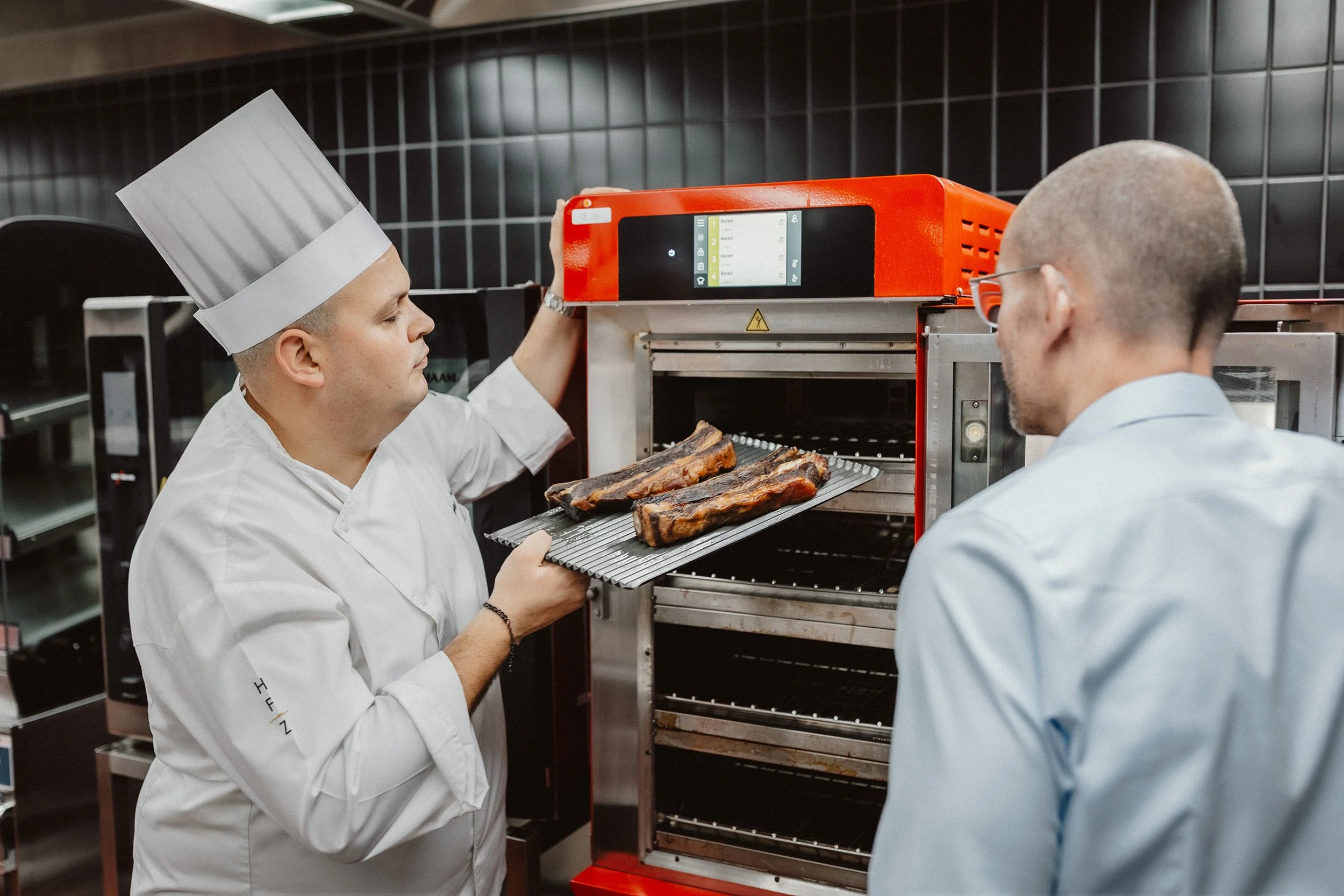 Koch legt Rippchen in einen Kokereinsatz in einer professionellen Küche