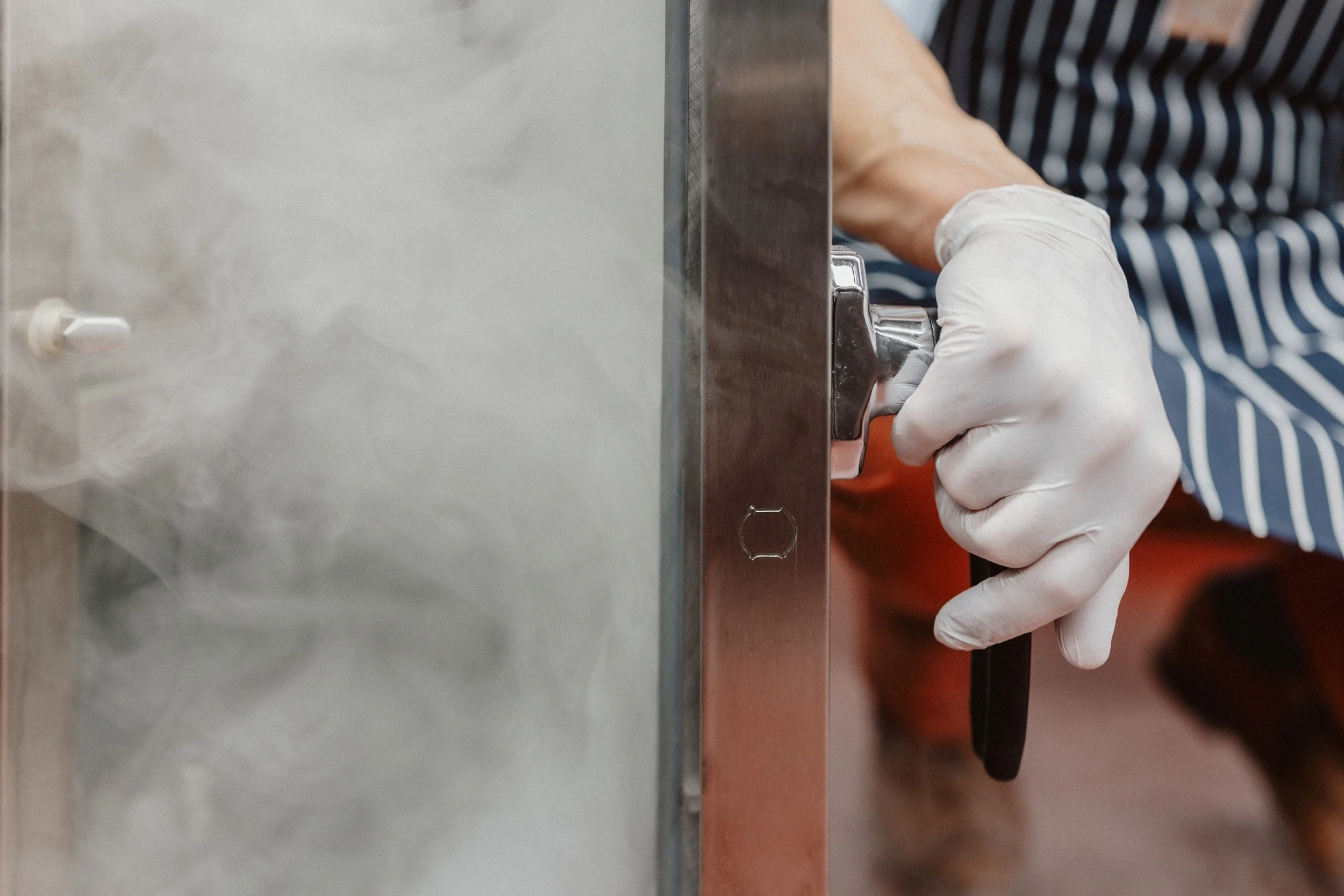 Hand mit weißer Handschuh bedient einen Brotschneider bei der Herstellung von Speisen.