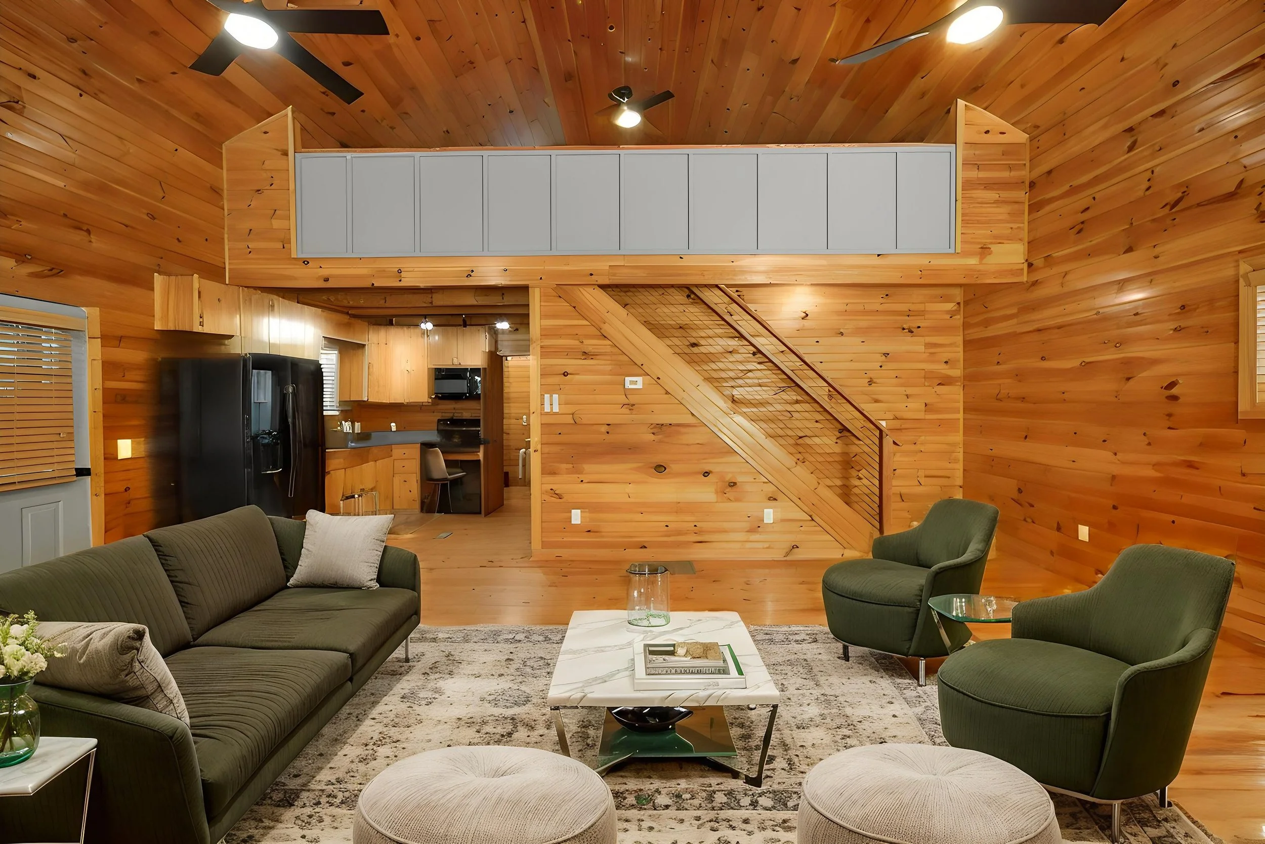 Living room with wooden walls and ceiling, featuring a fireplace, two armchairs, a sofa, and a coffee table with decorative items.