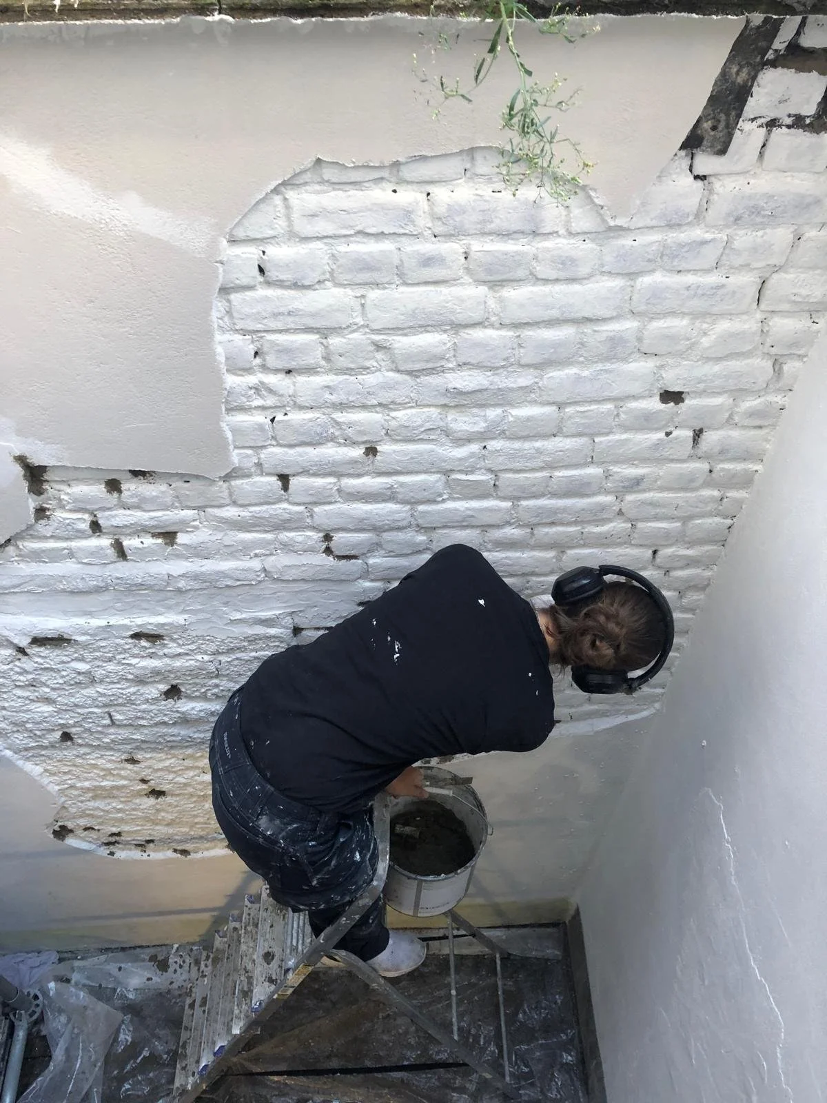 De schilder behandeld de bakstenen muur tegen vocht, regen en schimmel.