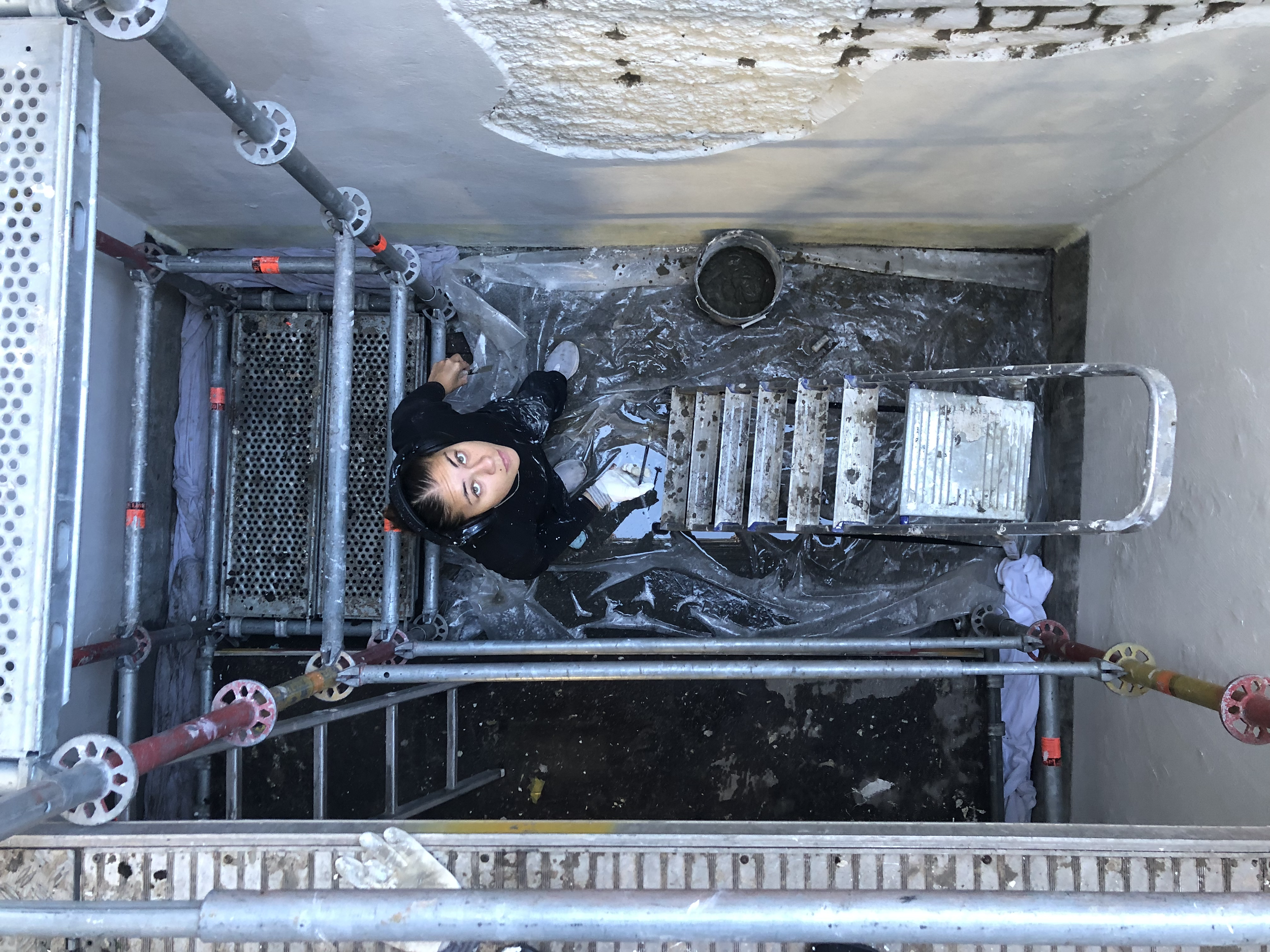 De schilder cementeert de grote spleten bij de de bakstenen 