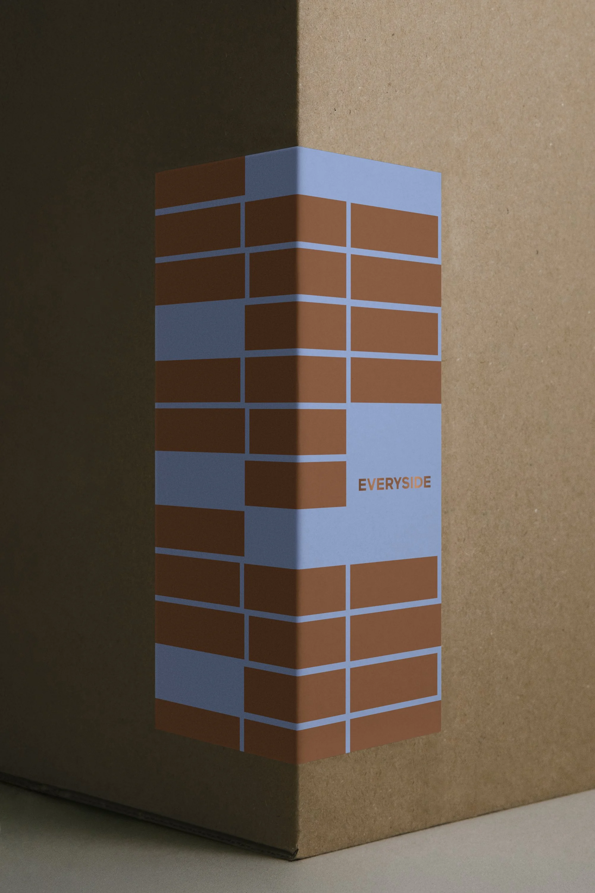 A cardboard box with a printed design resembling a brick wall and the word 'EVERYSIDE' on it.