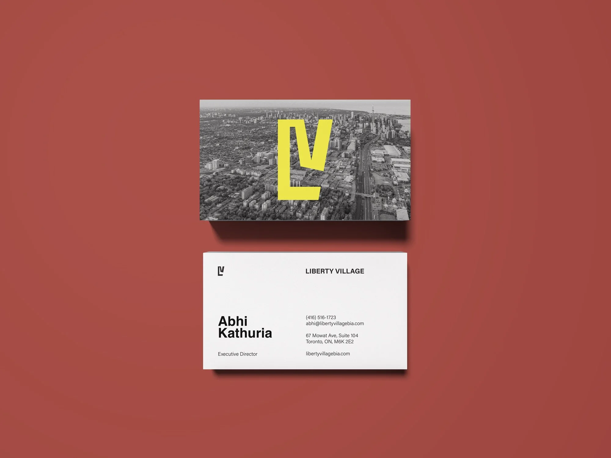 Business card and packaging design for Liberty Village, featuring a black and white aerial cityscape with a yellow LV logo on the box, and contact information on the card.