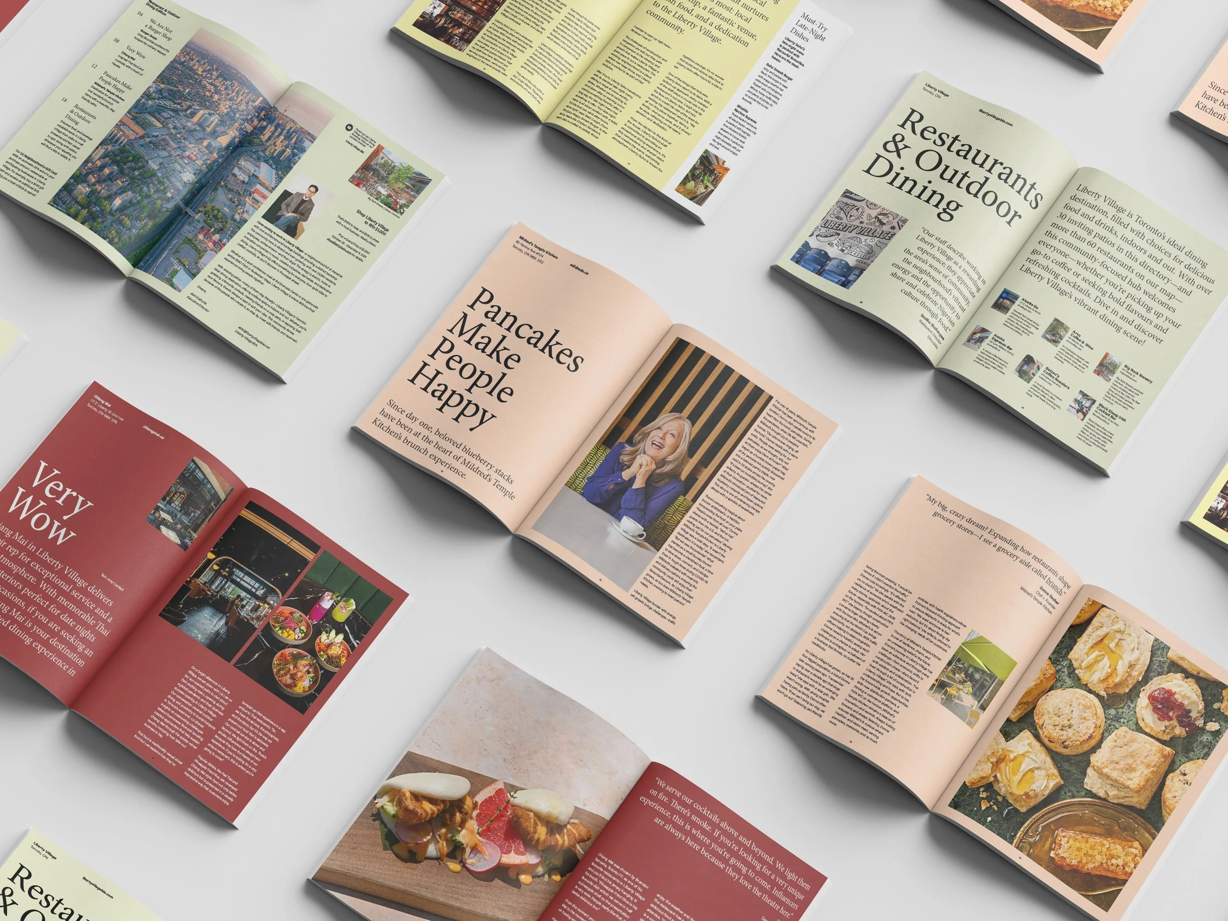 Multiple opened magazines displaying articles and images related to food, dining, and local attractions, arranged on a white surface.