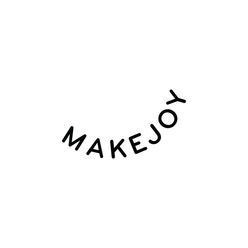 Neon sign with the words 'Make Joy' in uppercase, white letters against a black background.
