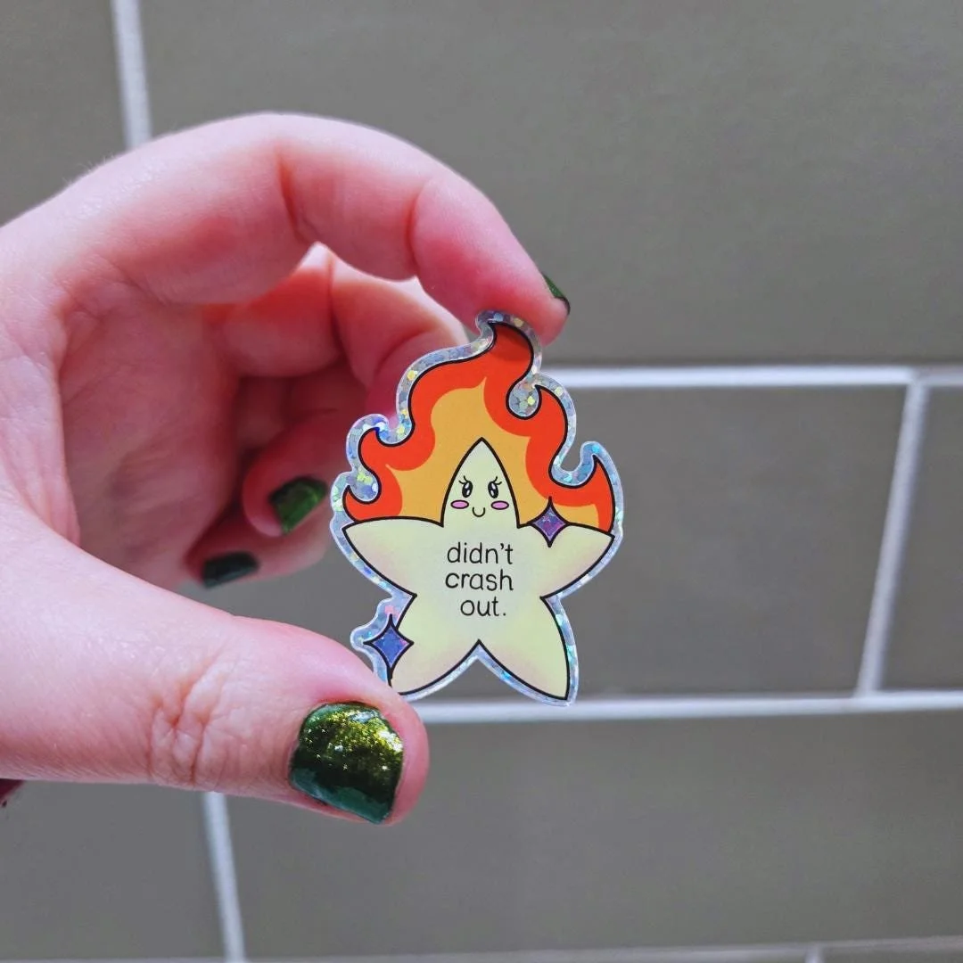 gold star with cute face that is on fire in the middle it says didn't crash out