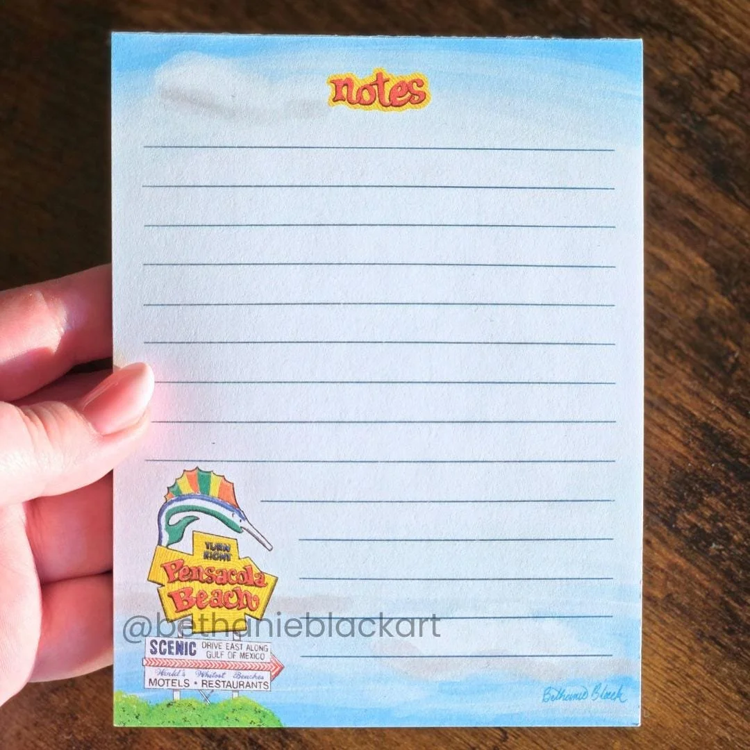 blue notepad with lines and the pensacola beach sign at the bottom left