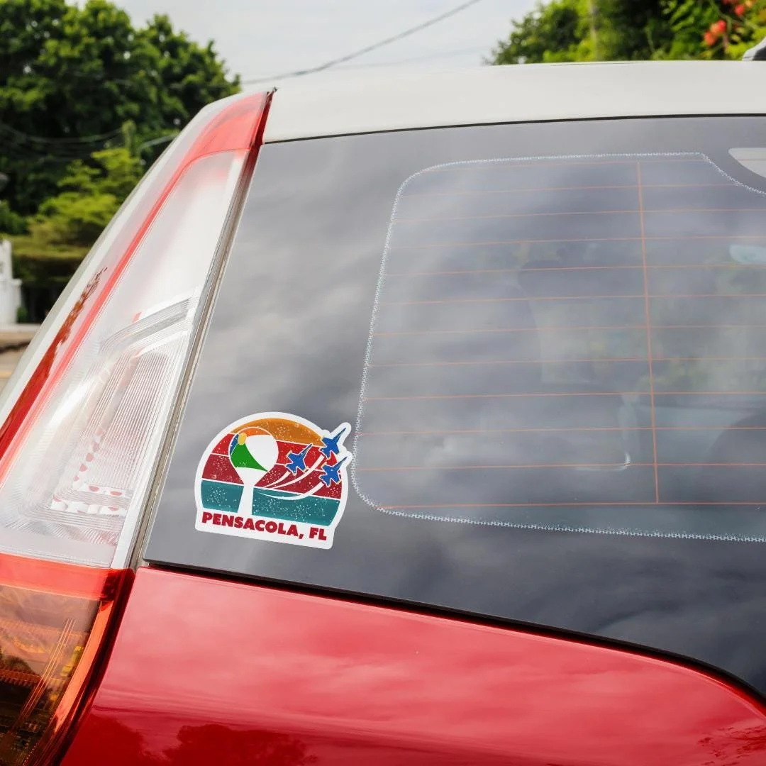 Pensacola, FL sticker pictured on the back of a red car's windshield