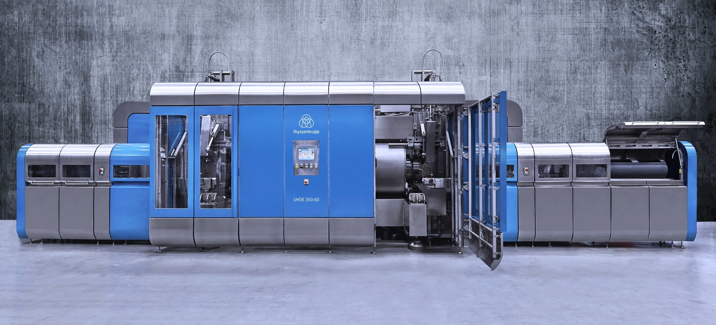 Large industrial HPP machine in a factory setting with blue and silver panels, used for High Pressure Processing manufacturing and processing.