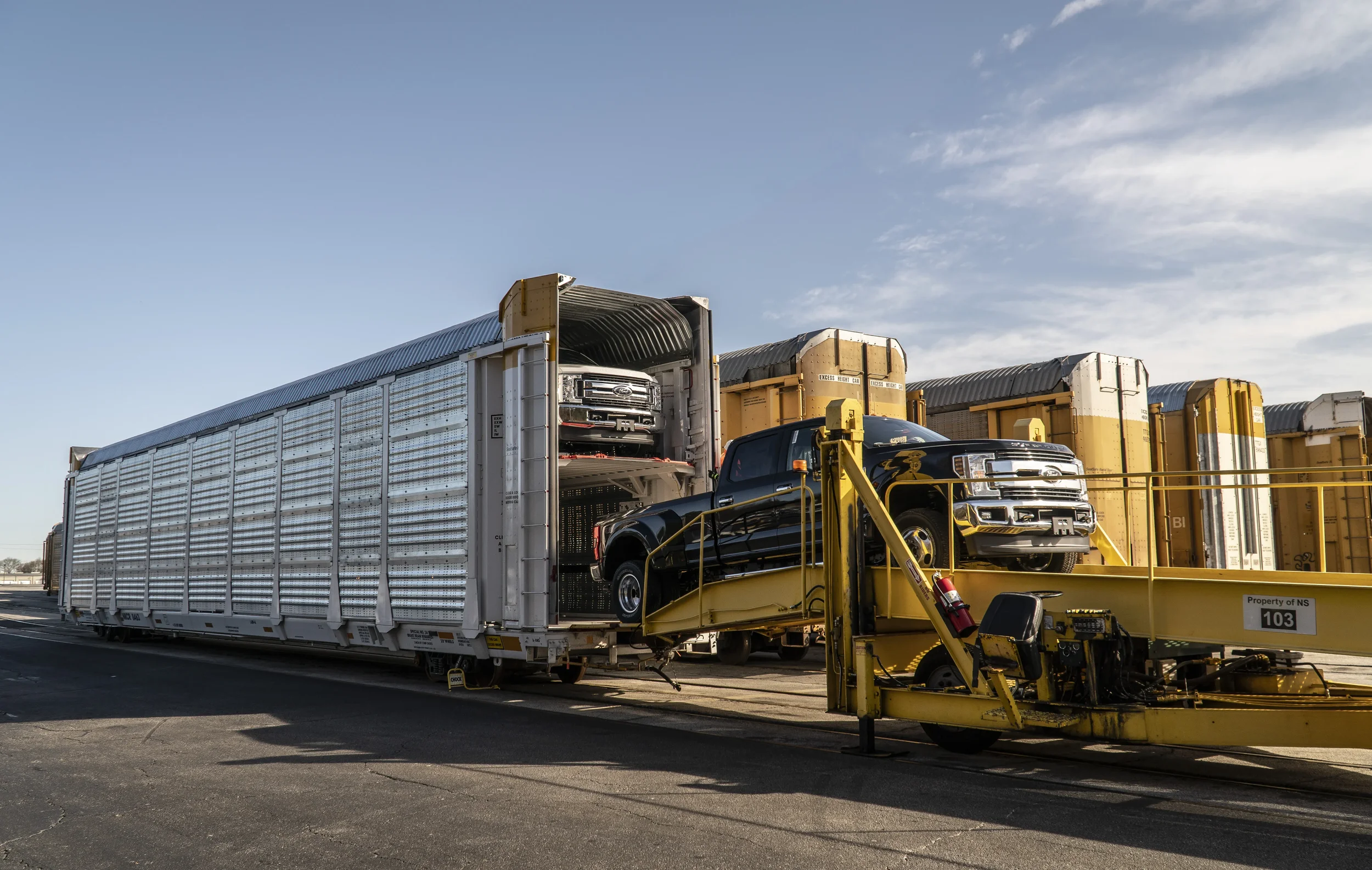 Industrial logistics photography showing finished vehicles being loaded into railcars at a rail transport facility, highlighting large-scale automotive distribution, freight operations, and supply chain efficiency.