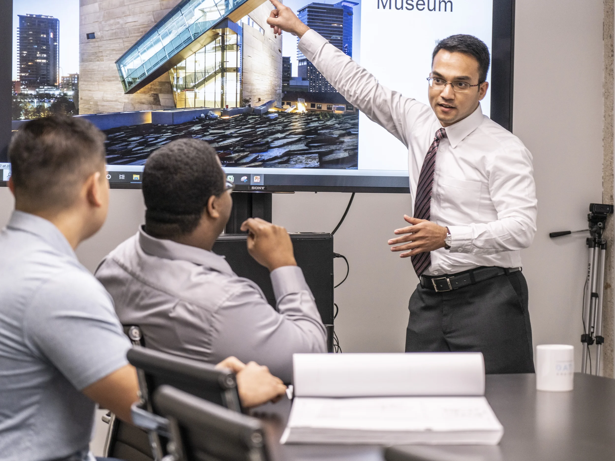 Corporate lifestyle photography capturing a professional presenting design concepts in a business meeting. Supports marketing narratives around expertise, collaboration, and leadership.