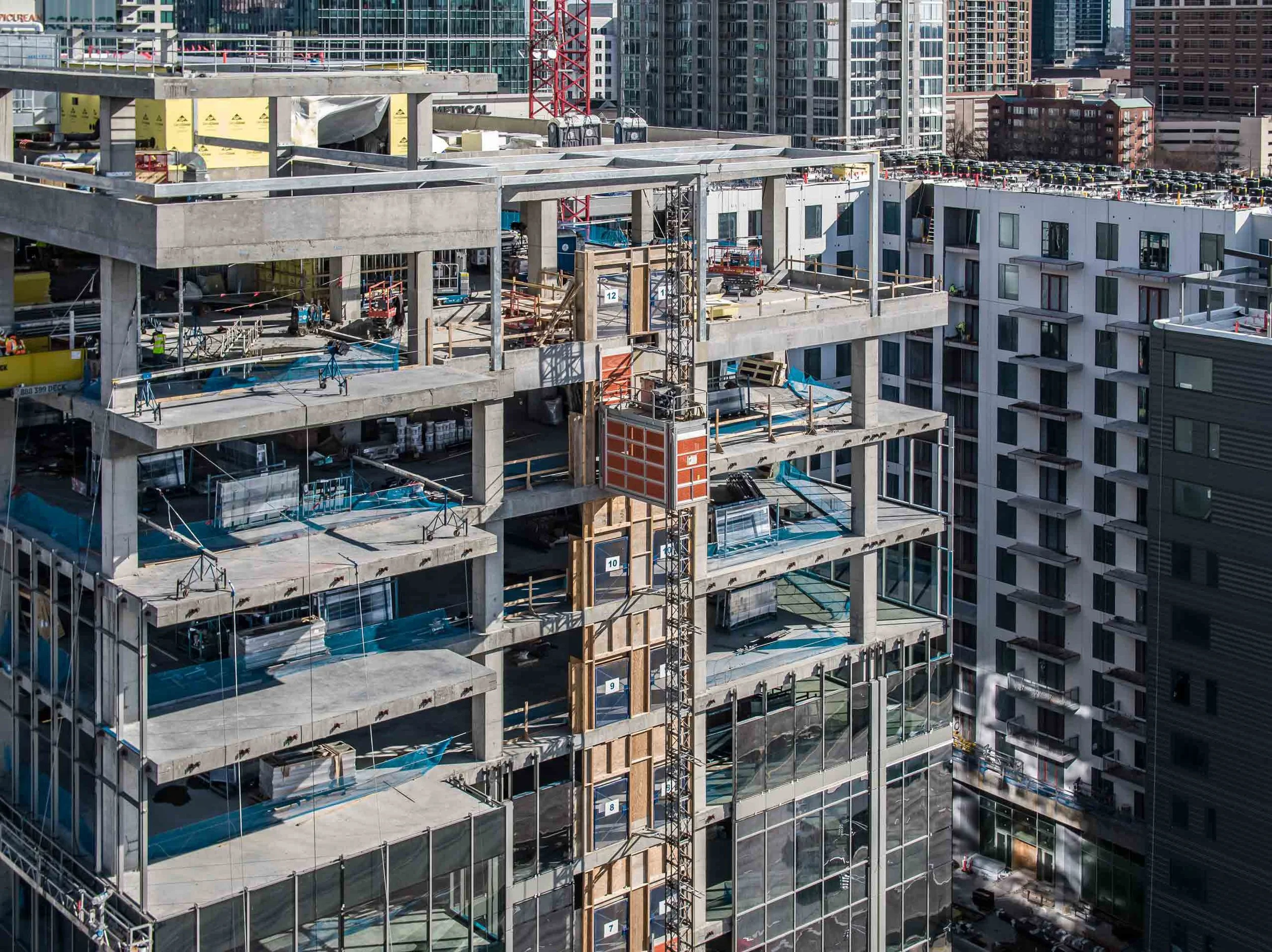 Drone photography documenting an active mid-rise construction project, showcasing concrete framing, vertical progress, and urban development for commercial construction marketing and project documentation.