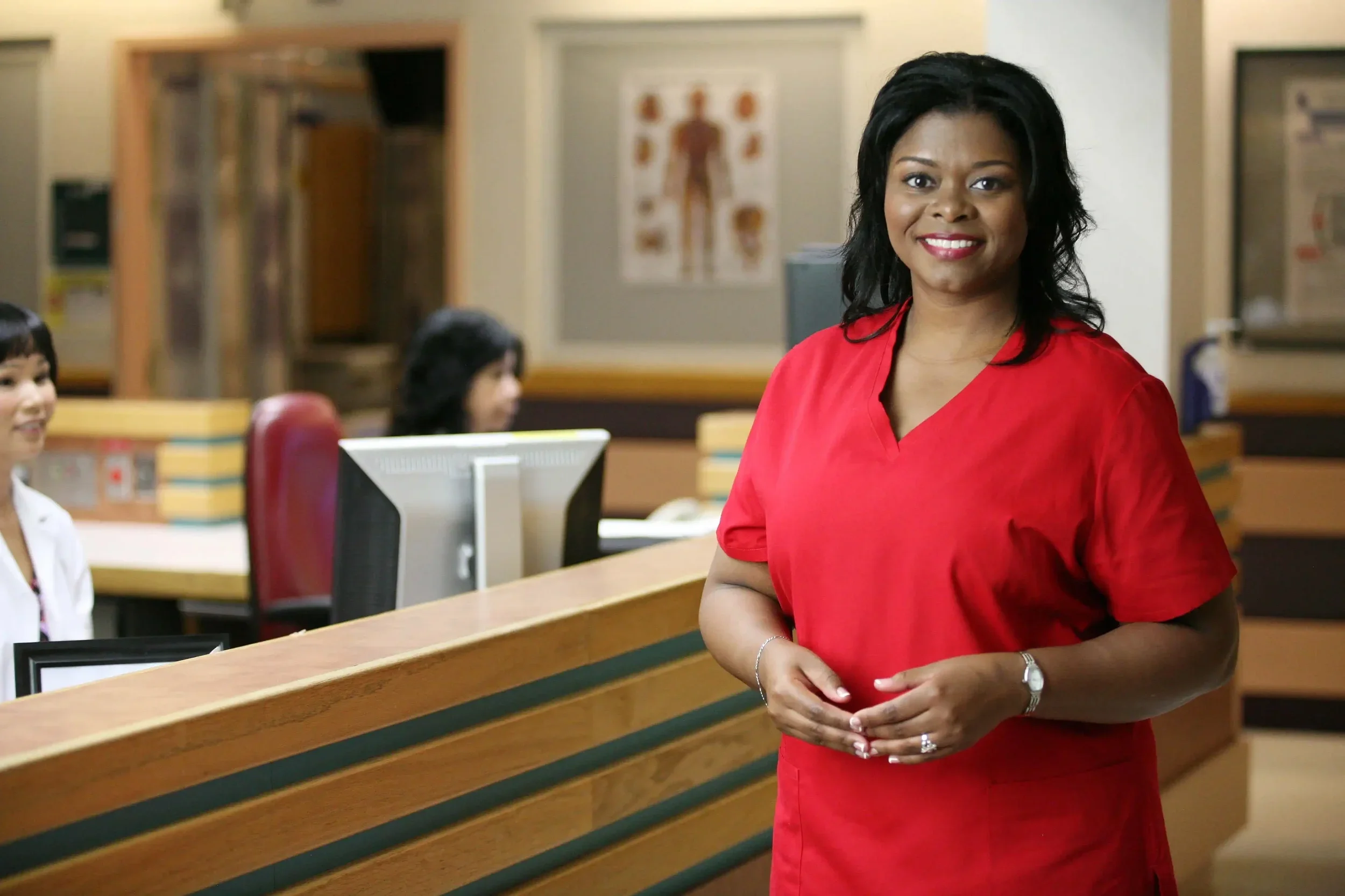 Corporate lifestyle portrait of a healthcare professional photographed in a clinical environment, conveying approachability, confidence, and professionalism. This image is well suited for healthcare organizations, medical practices, and corporate mar