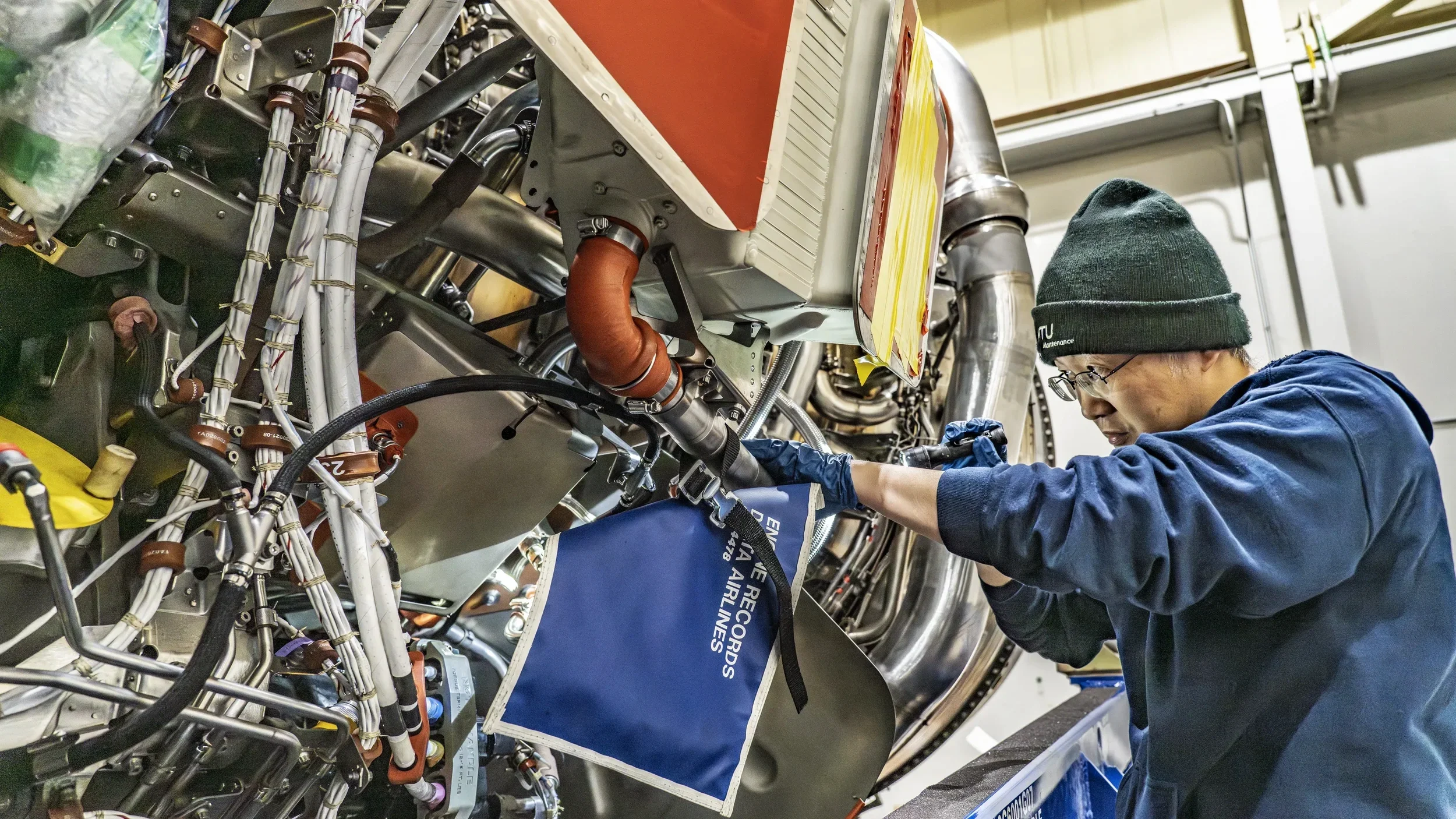 Industrial aerospace photography in Dallas showing a technician performing detailed maintenance on an aircraft engine, emphasizing precision engineering, safety procedures, and aviation maintenance expertise.