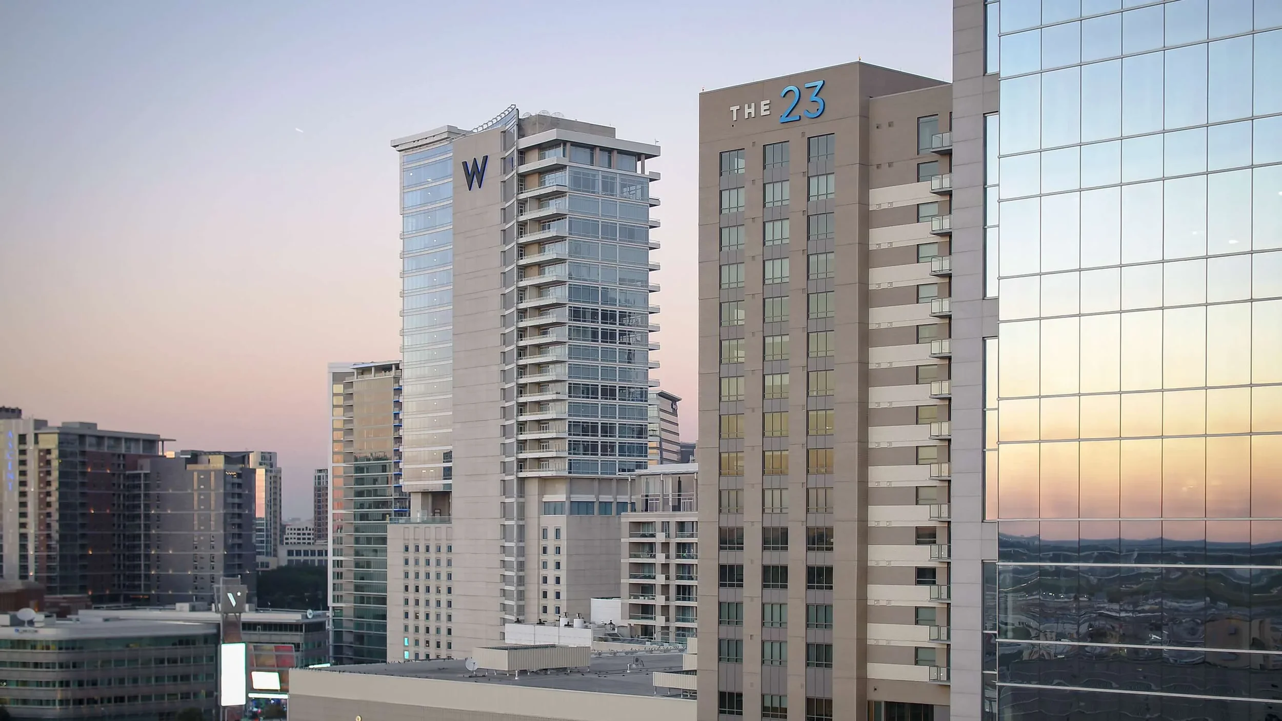 Drone photography of downtown Dallas high-rise buildings at sunset, highlighting architectural scale, reflective glass towers, and the city skyline during golden hour.