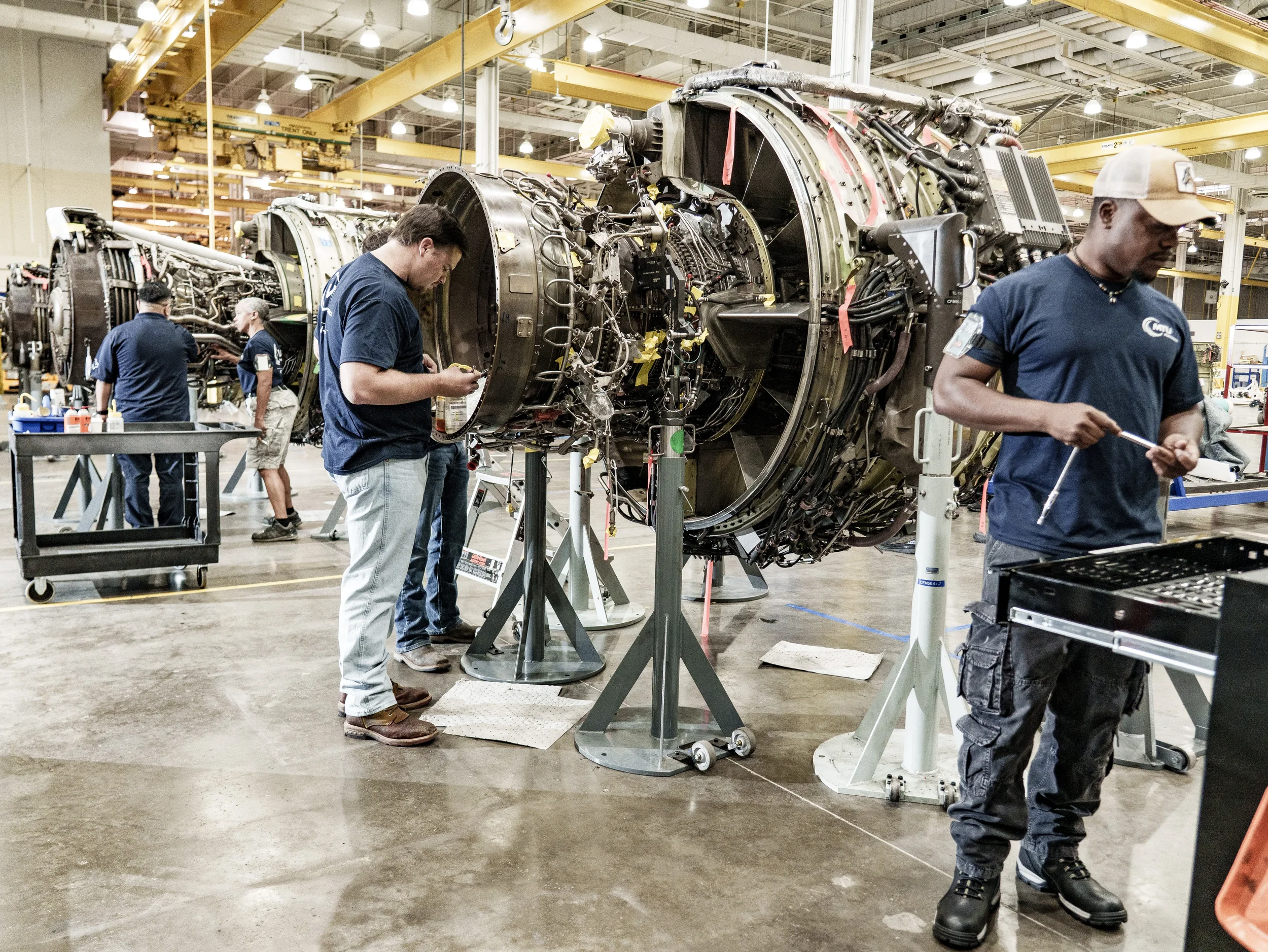 Industrial photography in Dallas capturing technicians performing maintenance on aircraft engines inside a manufacturing facility, highlighting aerospace engineering, precision assembly, and technical expertise.