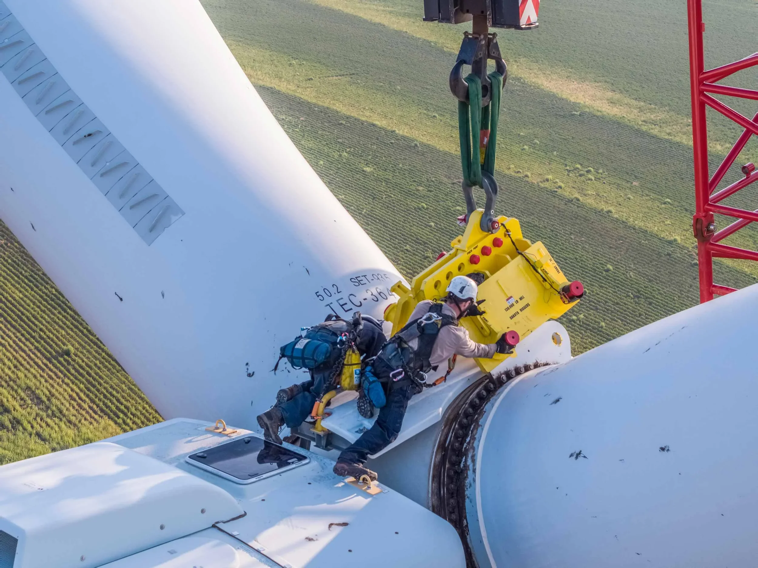 Aerial drone photograph of technicians positioning wind turbine components using heavy lift equipment, illustrating precision engineering, energy infrastructure installation, and industrial worksite documentation.