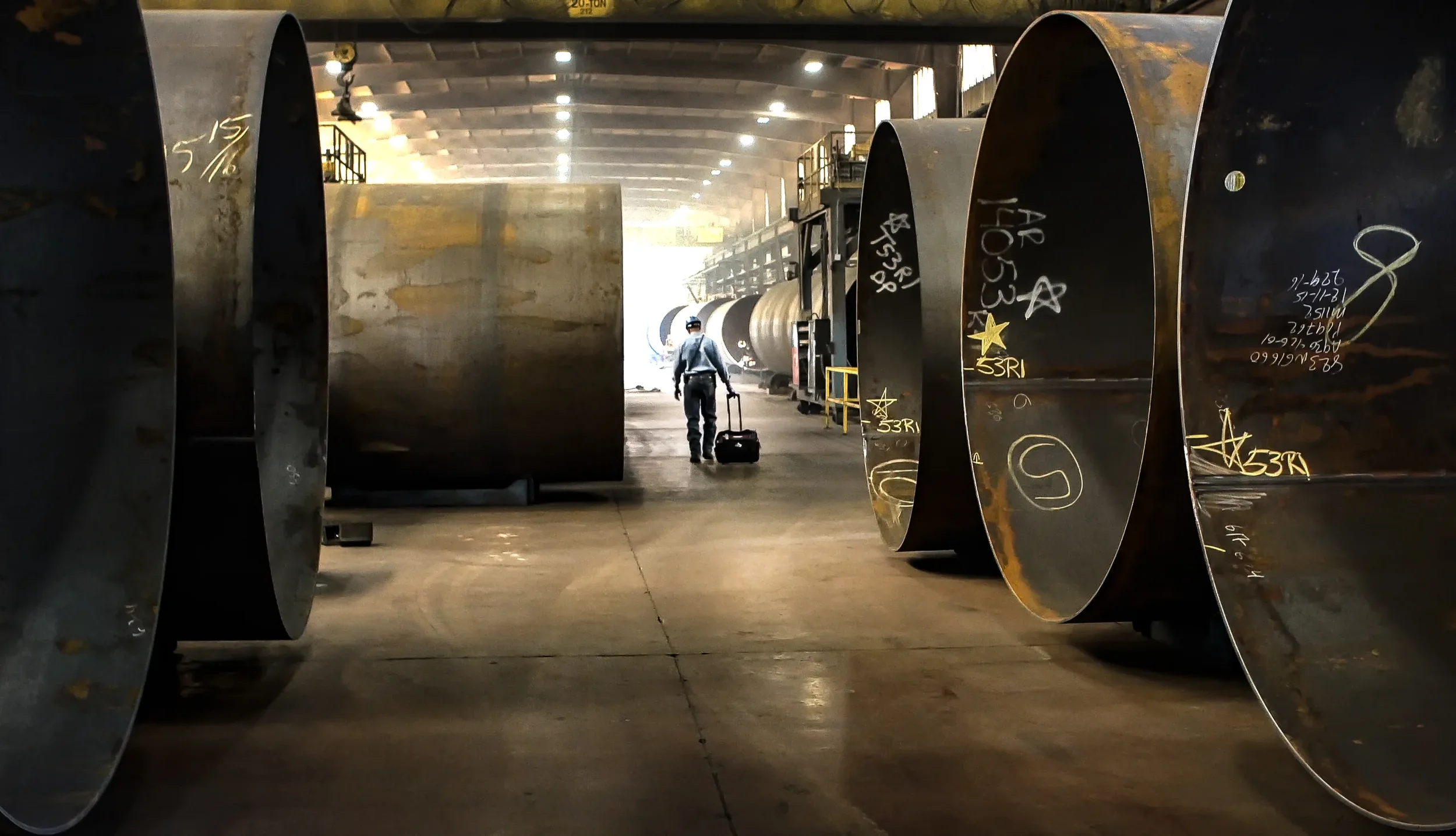 Dallas industrial photography capturing massive steel pipe sections staged inside a fabrication facility, emphasizing large-scale manufacturing, heavy industry, and industrial production environments.