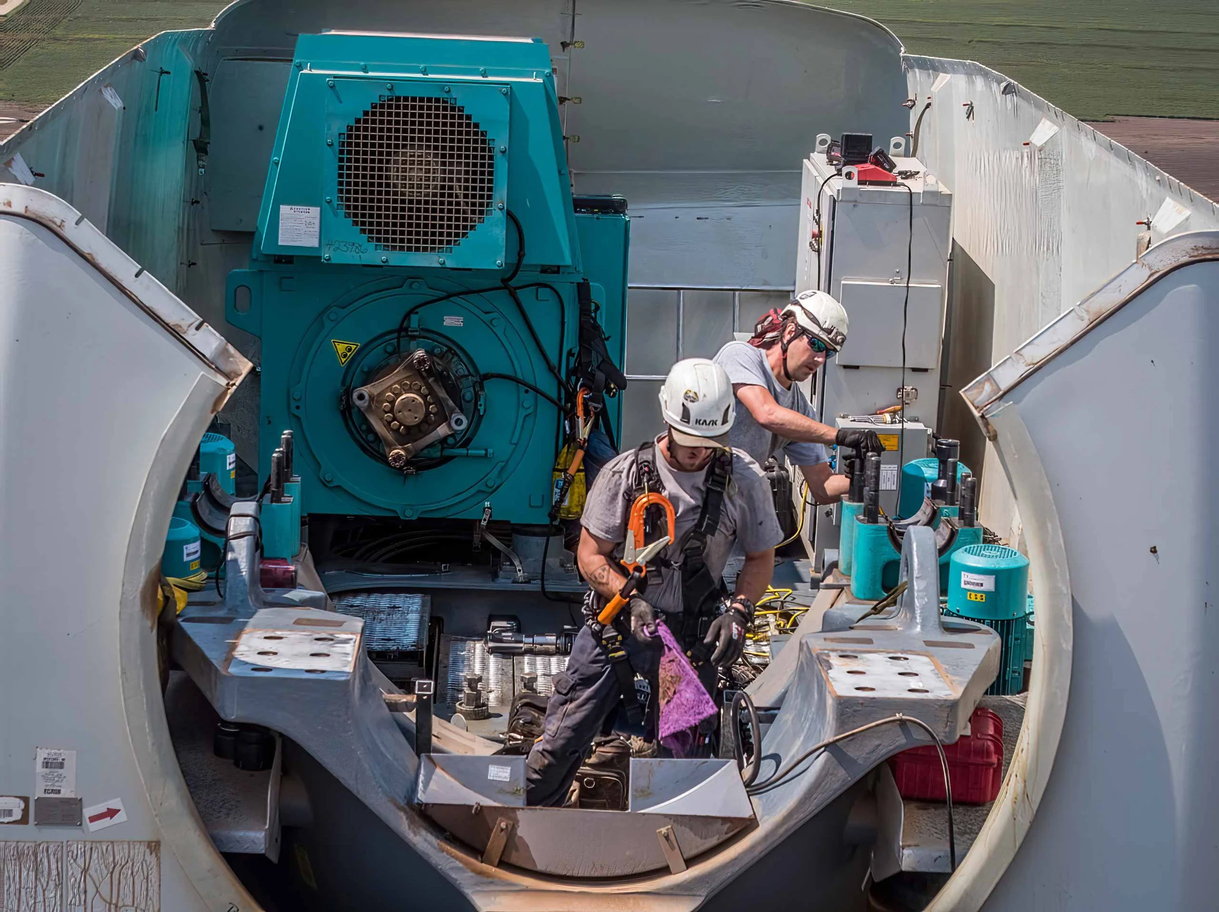 Aerial drone photography capturing wind turbine blade installation using a heavy-lift crane, highlighting precision engineering, renewable energy infrastructure, and large-scale industrial construction in an active wind farm environment.