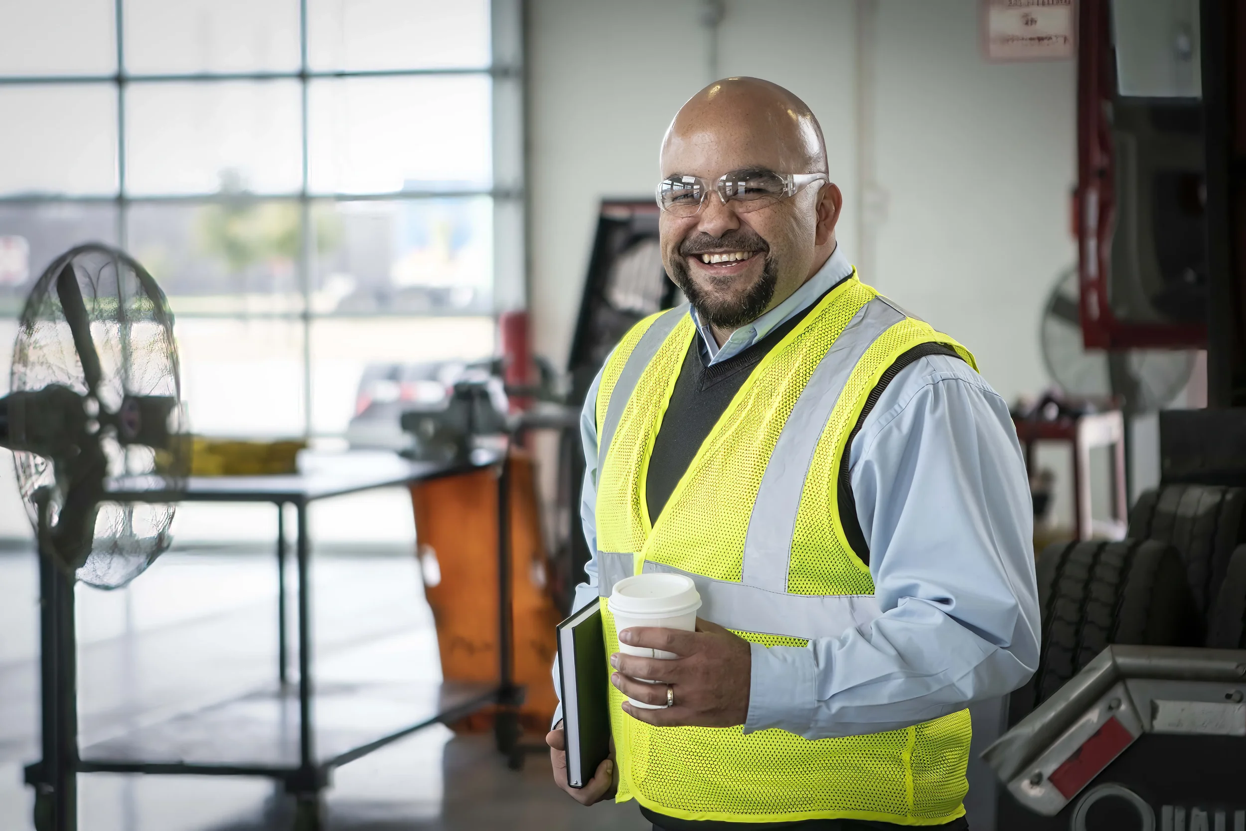 Corporate portrait of an operations leader photographed inside an active facility, conveying approachability, professionalism, and operational expertise. This image supports leadership profiles, internal communications, and corporate branding for ind