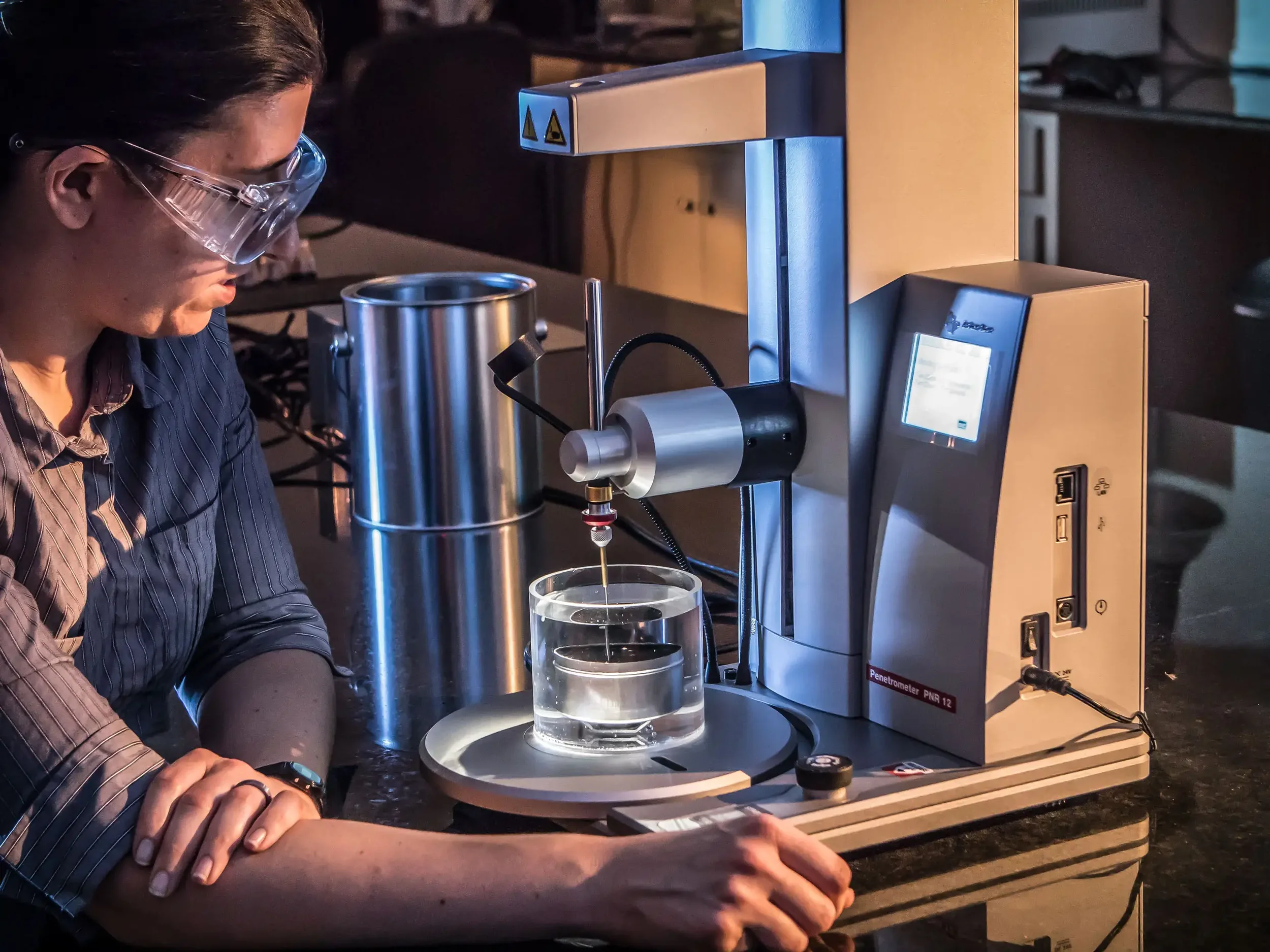 Dallas industrial photography showing a technician conducting precision material testing using specialized laboratory equipment, highlighting quality control, compliance standards, and advanced industrial testing processes.