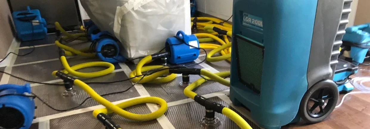 Hypochlorous acid generator connected to yellow hoses and blue device on a floor in a cleaning setup.