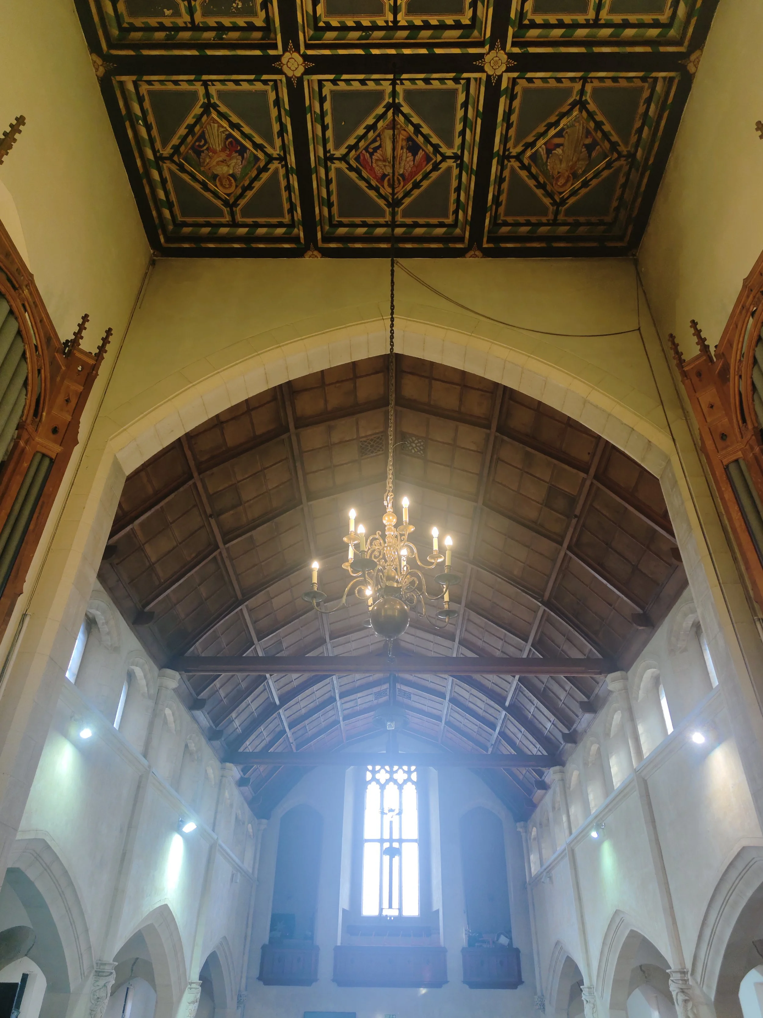 Penge Congregational Church.. Interior of a church or cathedral with high arched ceilings, a central chandelier with lit candles, and stained glass windows.