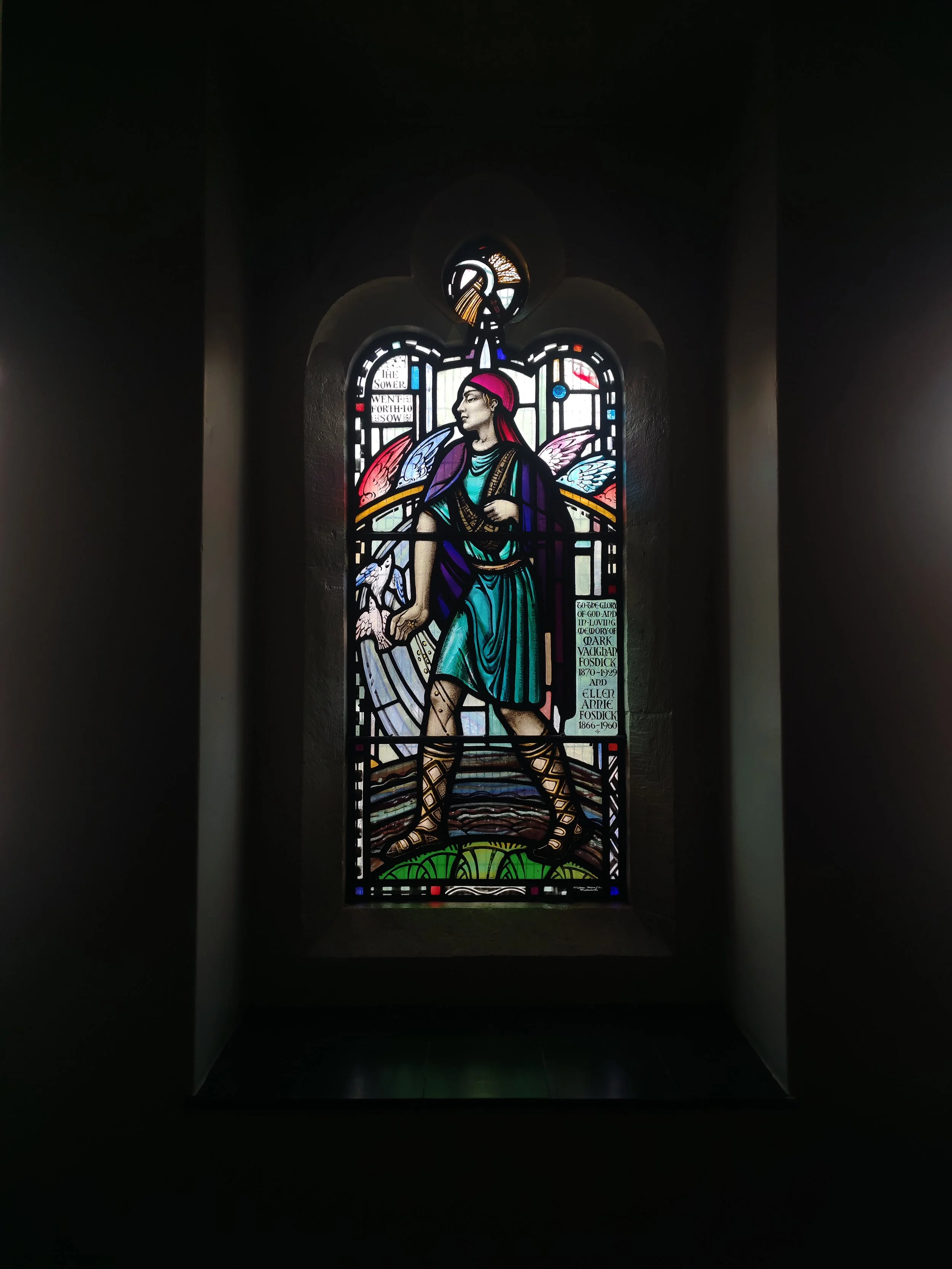 Penge Congregational Church. Colorful stained glass window depicting a winged figure walking forward, with an inscription panel and decorative elements around.