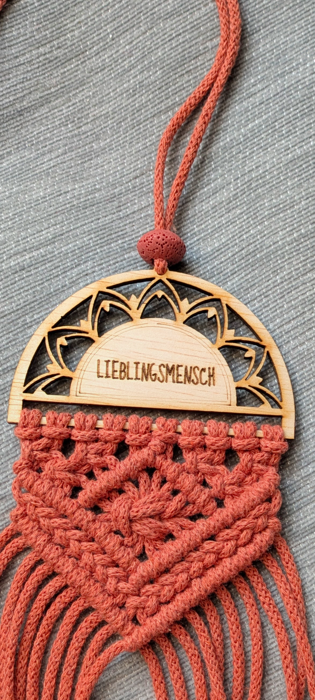 Detailaufnahme eines individuell gravierten Holz-Mandalas in einem handgeknüpften Makramee-Anhänger.