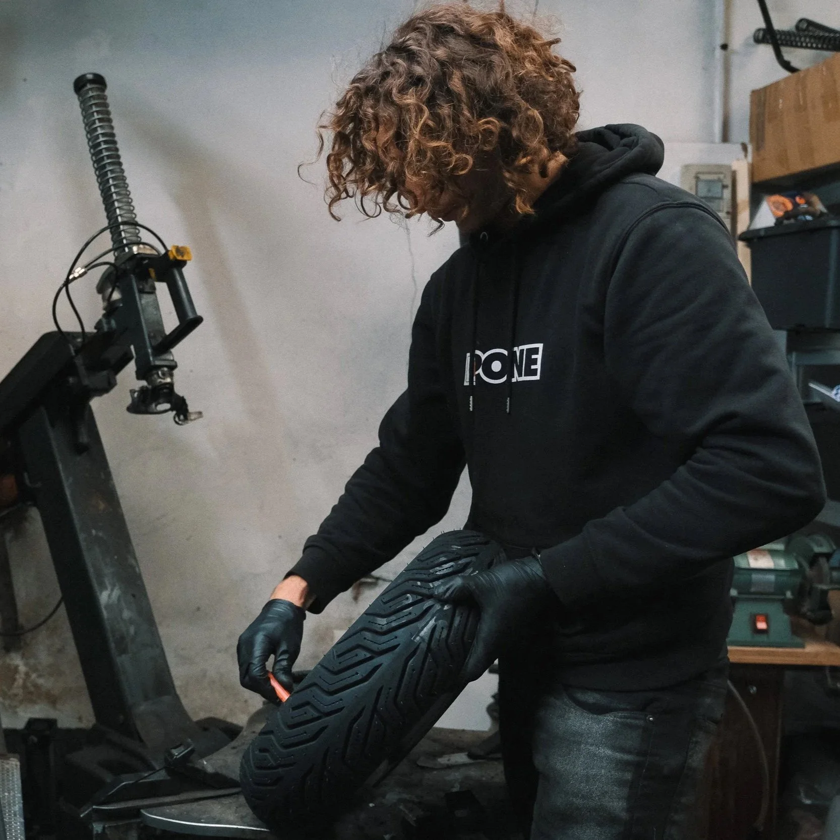 Une personne portant des gants noirs inspecte un pneu dans un atelier.