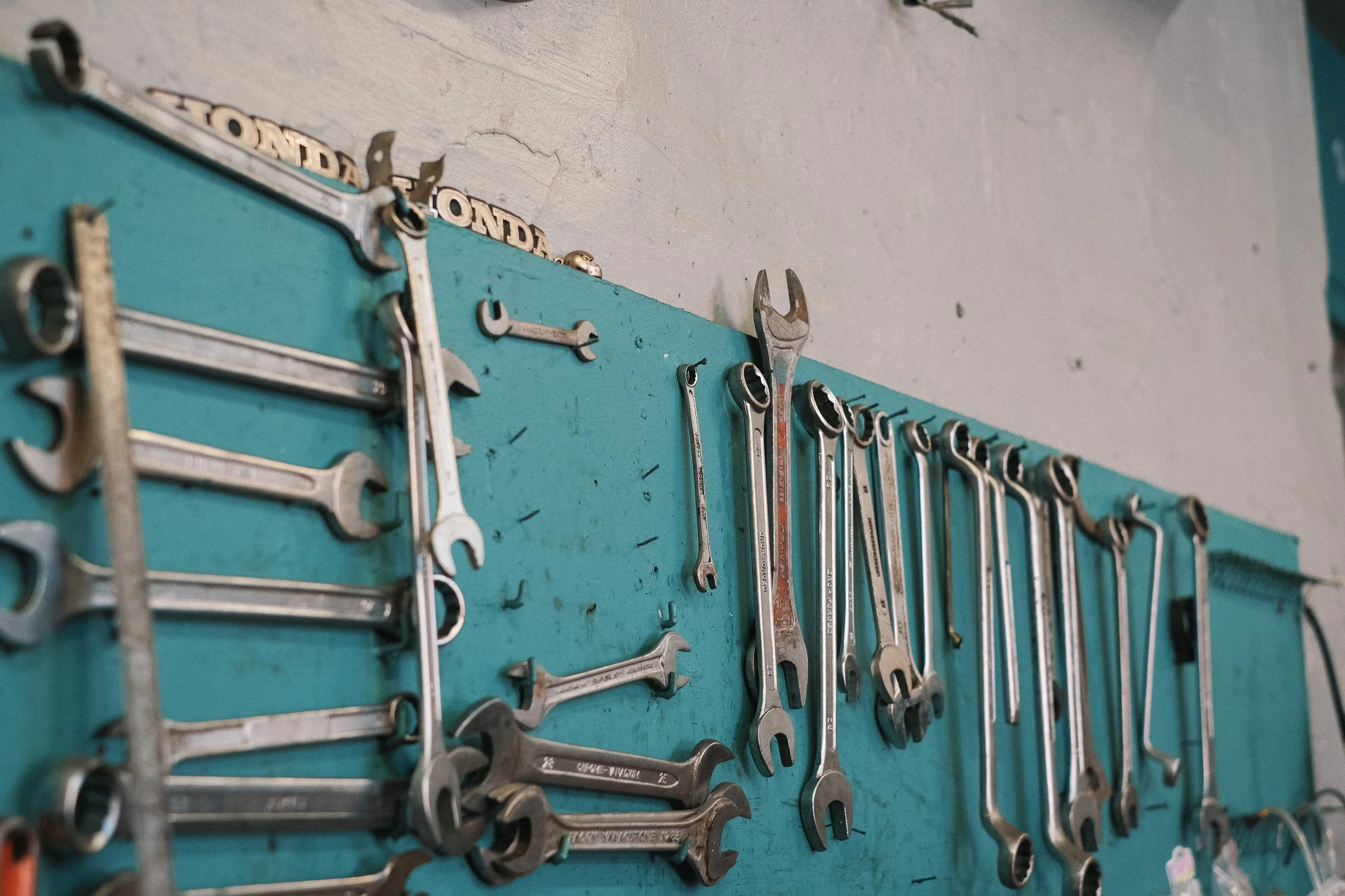 Jeu de clés et outils suspendus sur un panneau bleu dans un atelier mécanique.  Garage Akira motors entretient et réparation moto à Lyon.